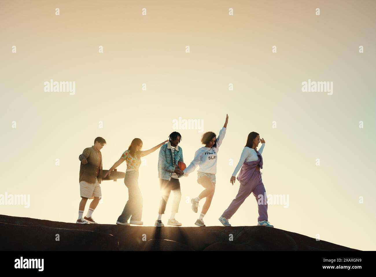 Un gruppo di amici che si diverte insieme al tramonto, creando ricordi e legami. Foto Stock