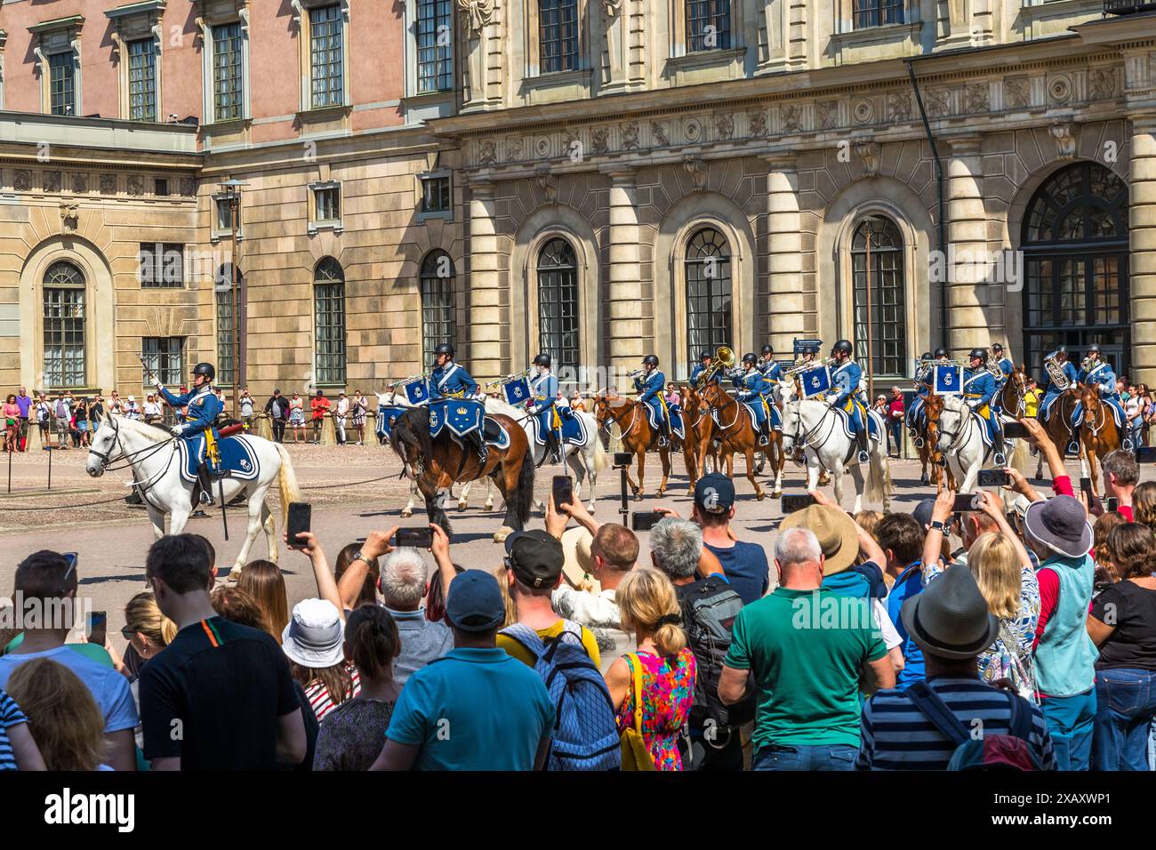 Parata equestre al Kungliga Slottet. I turisti tirano fuori i loro cellulari mentre la banda di cavalleria marcia dentro. Cerimonia della Guardia reale presso il Palazzo reale di Stoccolma. Cambio della guardia di fronte al Palazzo reale svedese di Stoccolma con accompagnamento musicale della banda montata. Yttre borggården, Stoccolma, Svezia Foto Stock