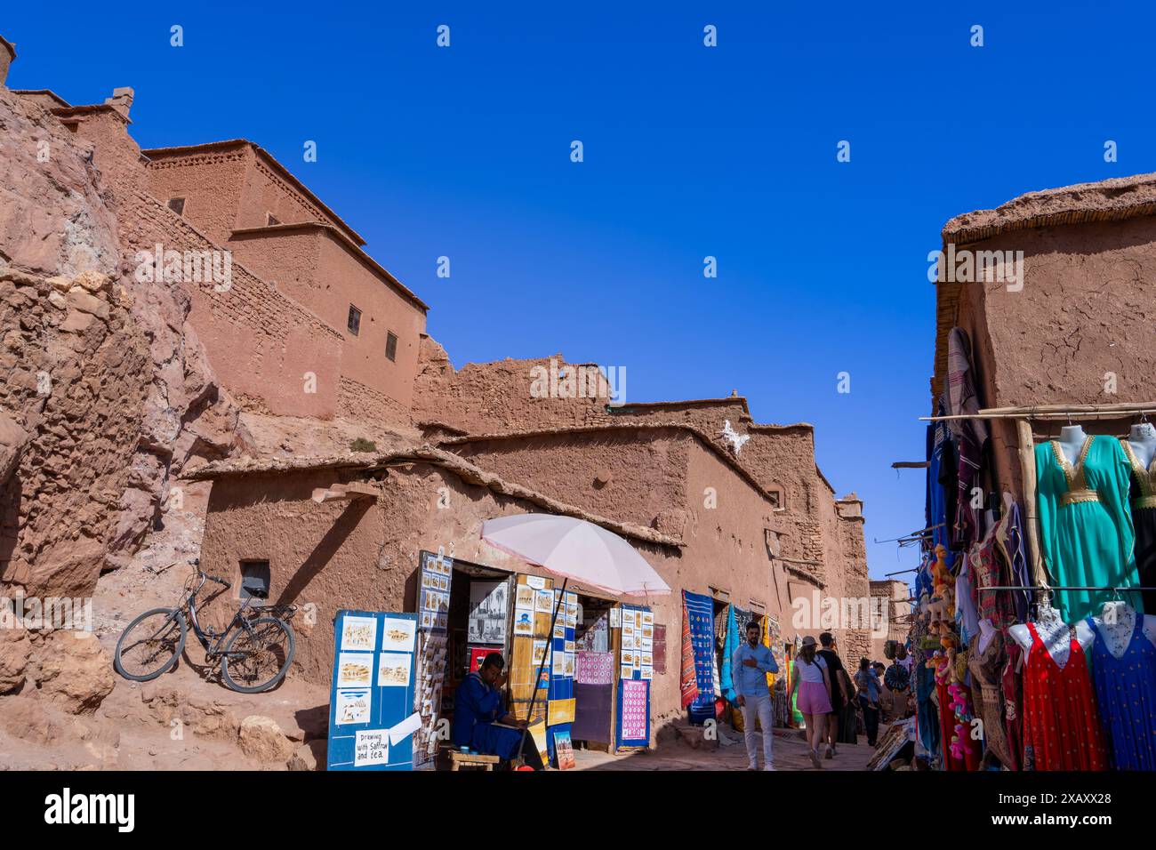 19 marzo 2024, Ait Benhaddou, Marocco: Bancarelle colorate vendono artigianato tradizionale sotto edifici storici in argilla. Foto Stock