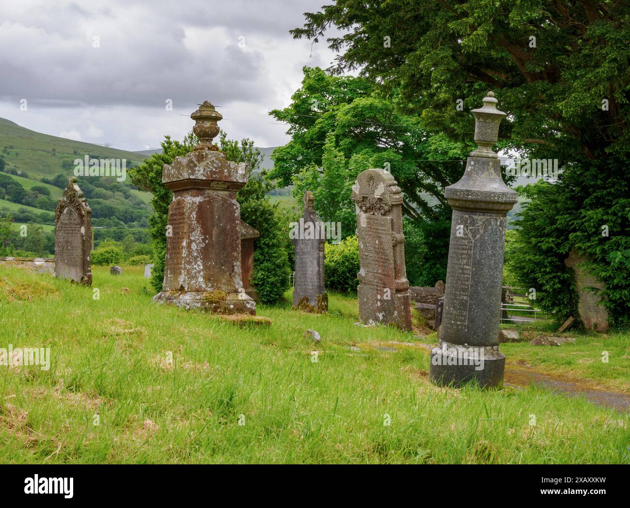 Uniche lapidi cilindriche su tombe nel cimitero di St Simon e St Jude a Llanddeusant, nei Brecon Beacons, Galles del Sud, Regno Unito Foto Stock