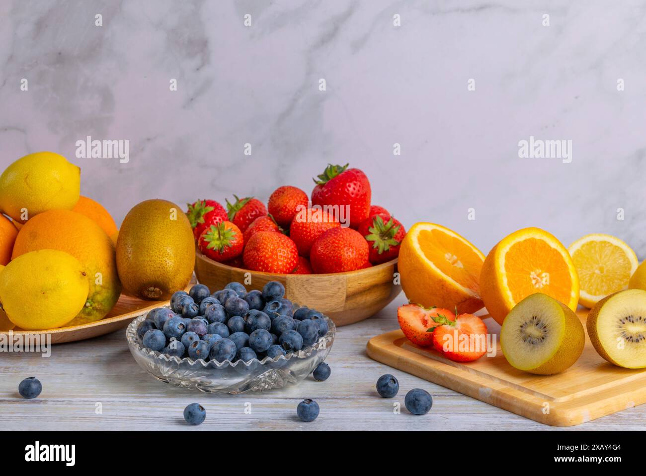 Natura morta armoniosa di vari frutti, fragole, limoni, arance, kiwi e mirtilli, parzialmente tagliato a fette Foto Stock