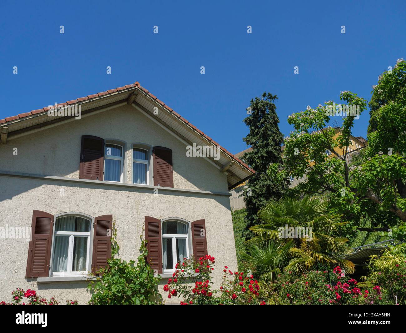 Casa residenziale con persiane marroni e un giardino lussureggiante al sole, Meersburg, lago di Costanza, Germania Foto Stock