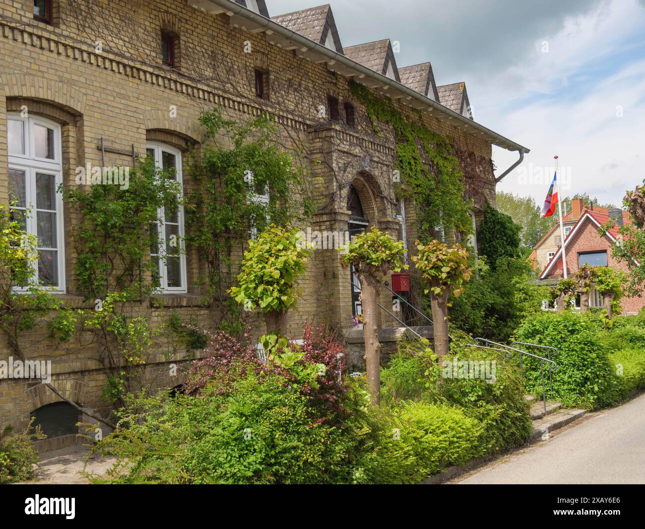 Edificio storico con facciate ricoperte di edera, finestre e cielo nuvoloso, Arnis, Schleswig-Holstein, Germania Foto Stock