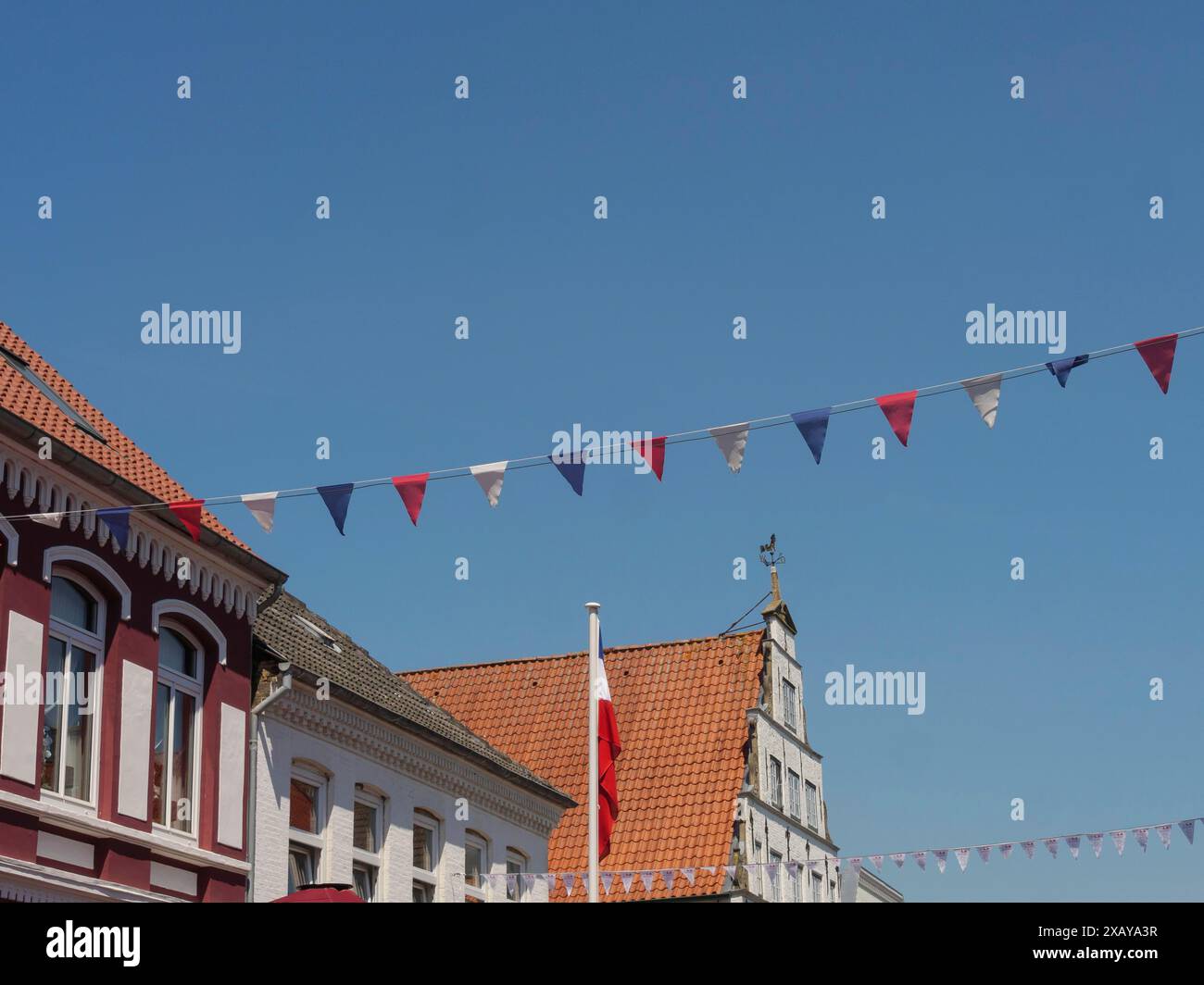 Facciata della casa con bandiere di carta colorata che si estendono sul cielo blu, friedrichstadt, schleswig-holstein, germania Foto Stock