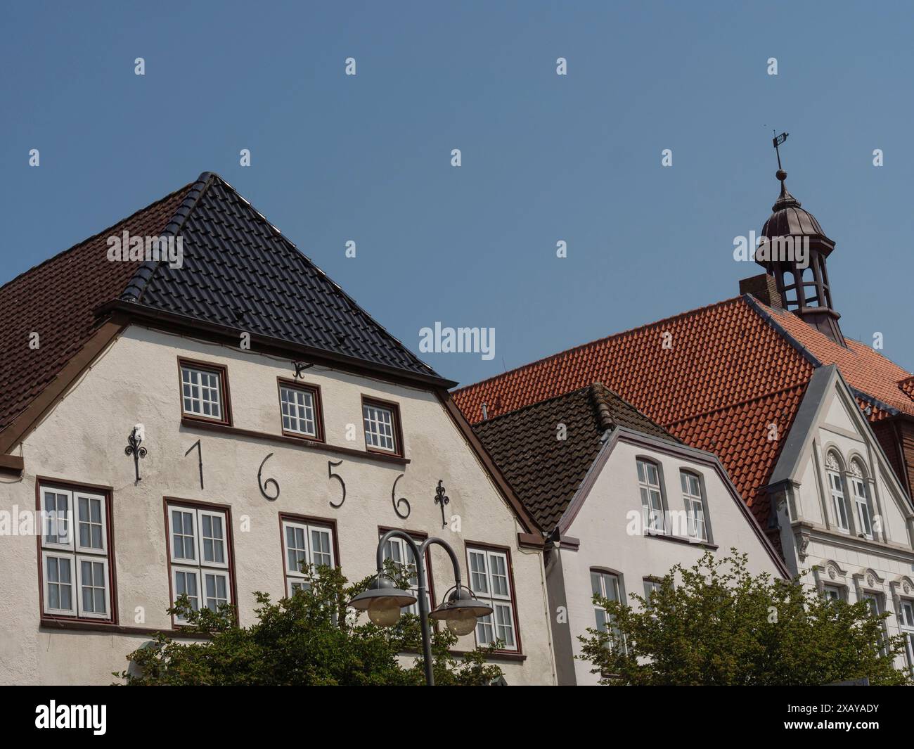 Fila di edifici storici con tetti di diverse forme, un numero civico e finestre sotto un cielo blu, husum, schleswig-holstein, germania Foto Stock