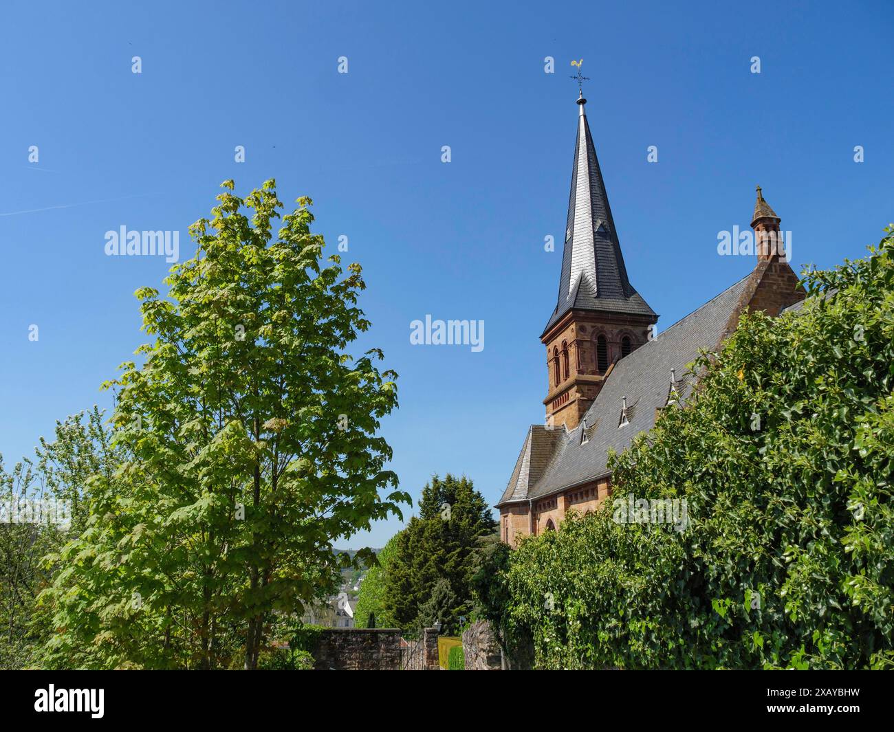 Torre della Chiesa in un ambiente verde ed estivo sotto un cielo blu brillante, Saarburg, Germania Foto Stock