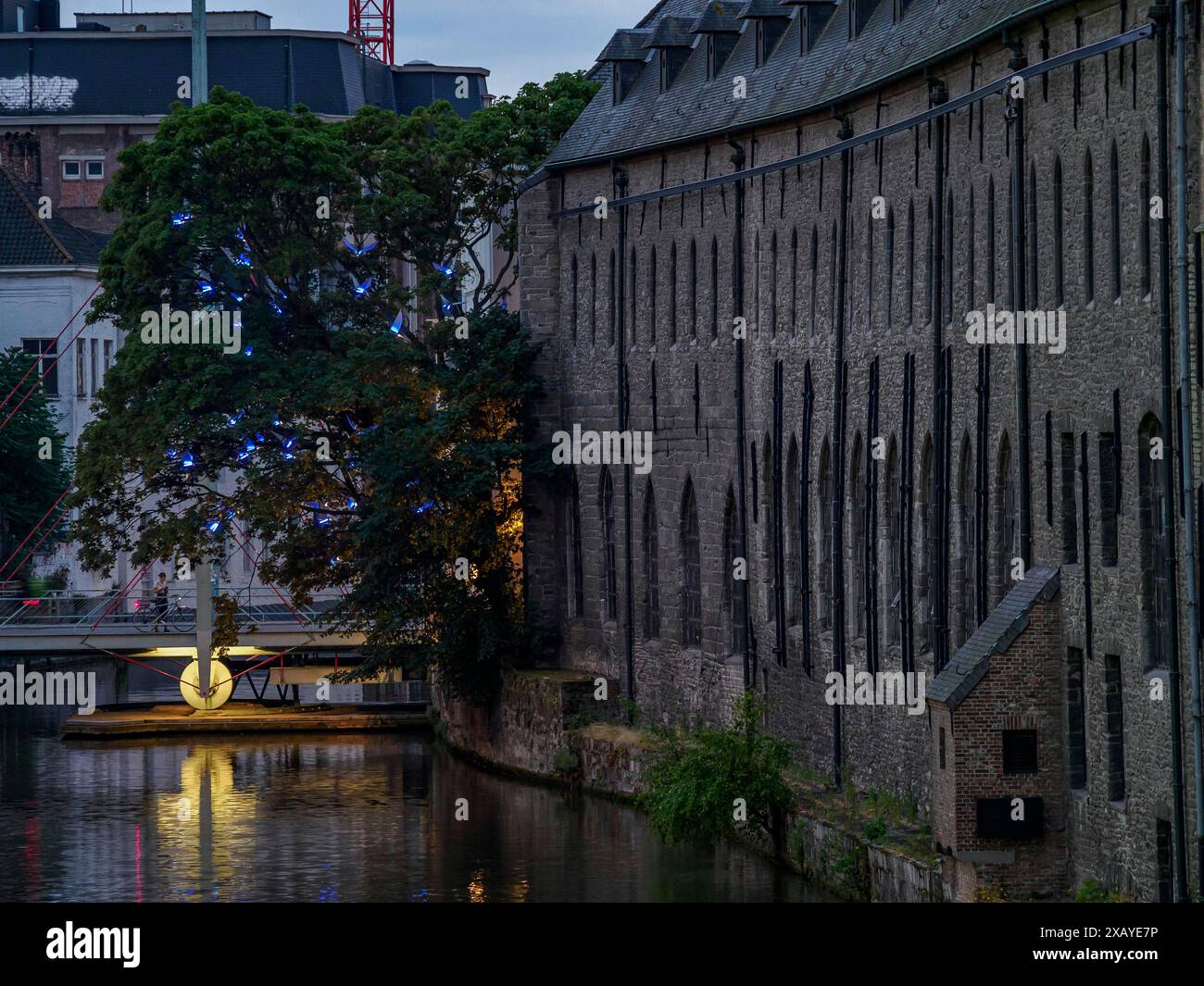Edificio storico sulla riva del canale al crepuscolo, passaggi e alberi illuminati, Gand, Belgio Foto Stock