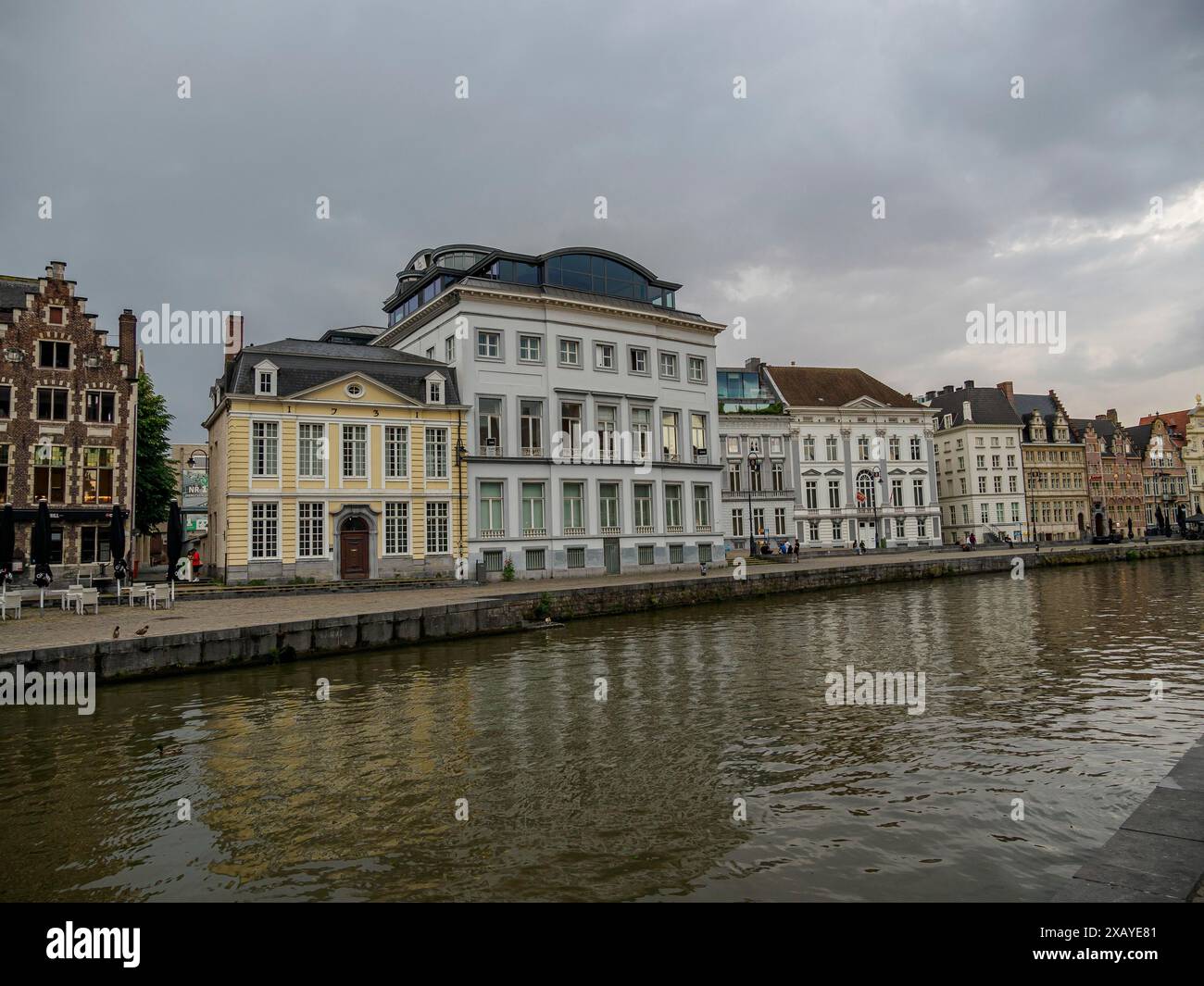 Edifici storici lungo un fiume sotto un cielo nuvoloso, che si riflettono nell'acqua, Gand, Belgio Foto Stock