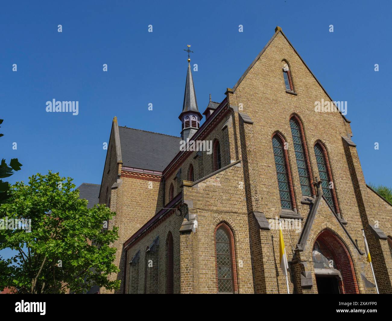 Chiesa storica con finestre blu e alberi in primo piano, cielo limpido, ostenda, Belgio Foto Stock