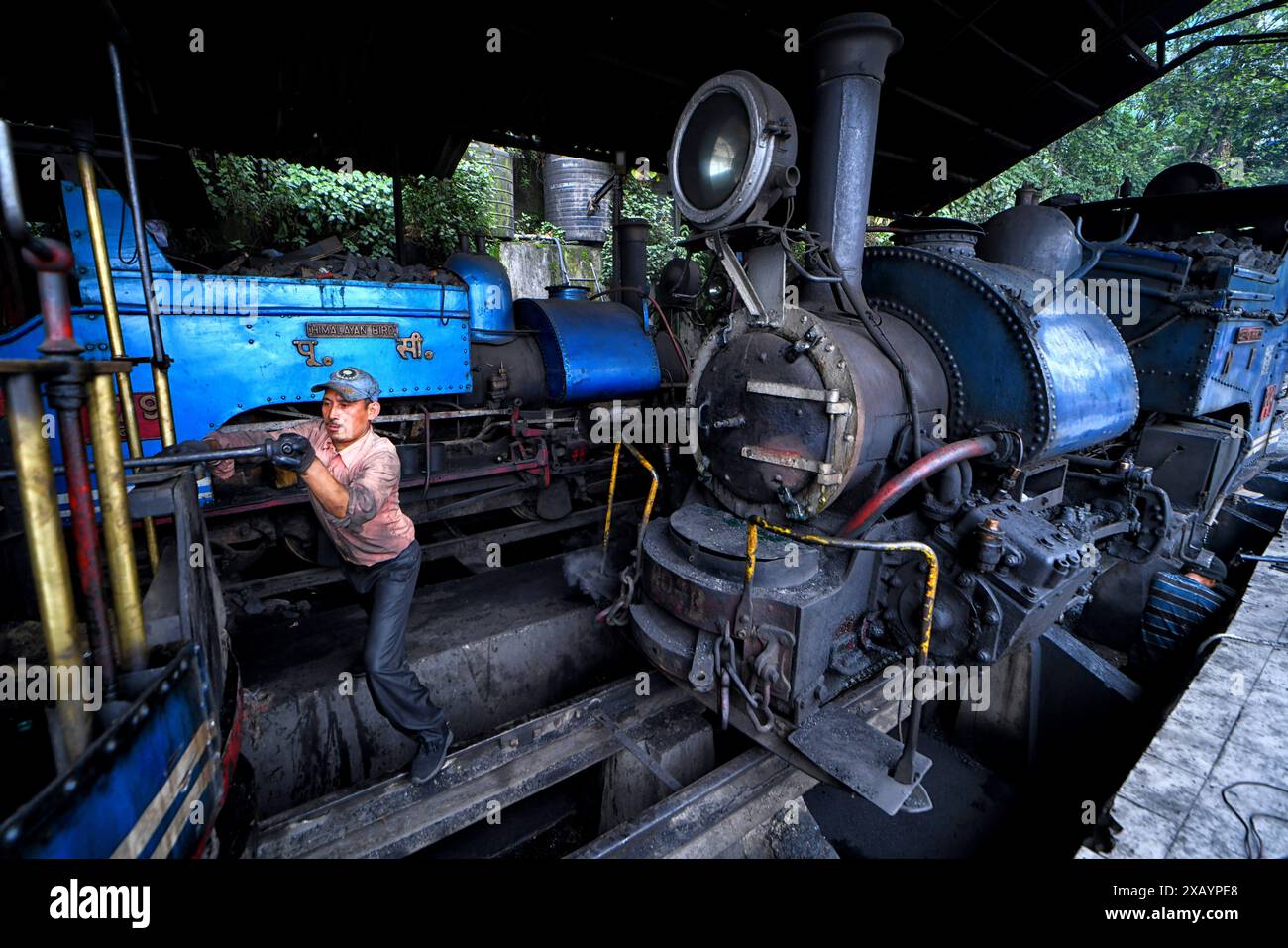 Un meccanico del dipartimento ferroviario controlla una locomotiva a vapore alla stazione ferroviaria di Darjeeling. La Darjeeling Himalayan Railway, nota anche come "Toy Train", è un treno ferroviario a scartamento ridotto costruito tra il 1879 e il 1881. La ferrovia si sposta fino a un livello di altitudine di 2.200 metri (7.218 piedi). Quattro moderne locomotive diesel gestiscono la maggior parte dei servizi di linea; tuttavia i treni turistici giornalieri da Darjeeling a Ghum (la stazione ferroviaria più alta dell'India) sono gestiti dalle locomotive a vapore vintage di costruzione britannica classe B. Il DHR è stato dichiarato patrimonio dell'umanità dall'UNESCO nel 1999. (Foto di Avishe Foto Stock