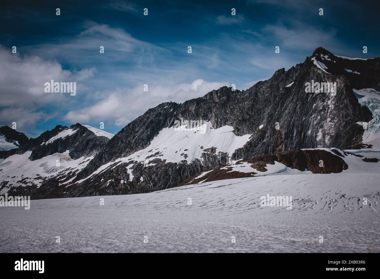 Una vista mozzafiato del ghiacciaio dell'Alaska, che mette in risalto le aspre cime delle montagne e gli ampi campi innevati sotto un cielo azzurro. Questa foto cattura t Foto Stock