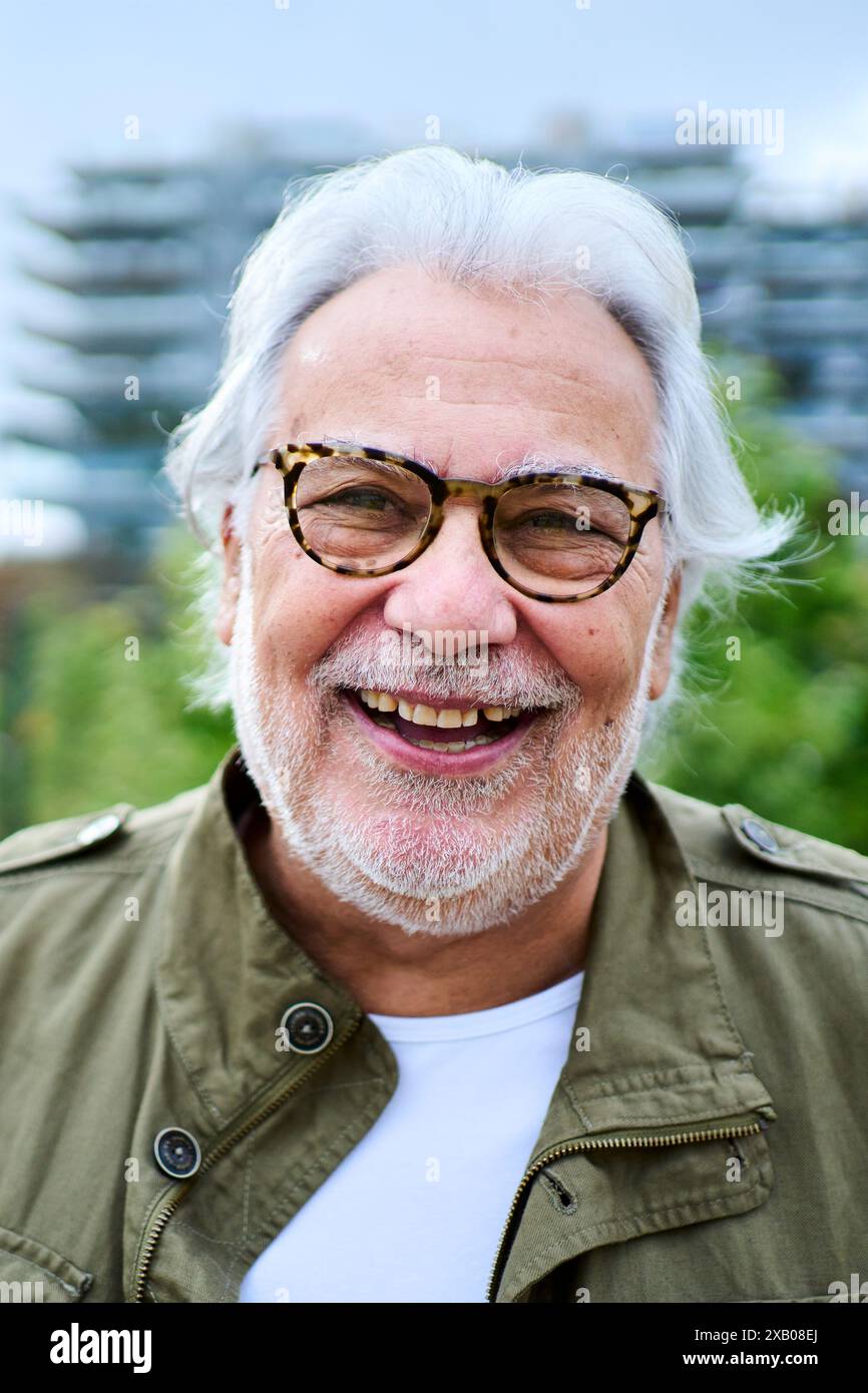 Ritratto di un uomo anziano caucasico maturo felice in piedi all'aperto con giardino di sfondo non focalizzato. Foto Stock
