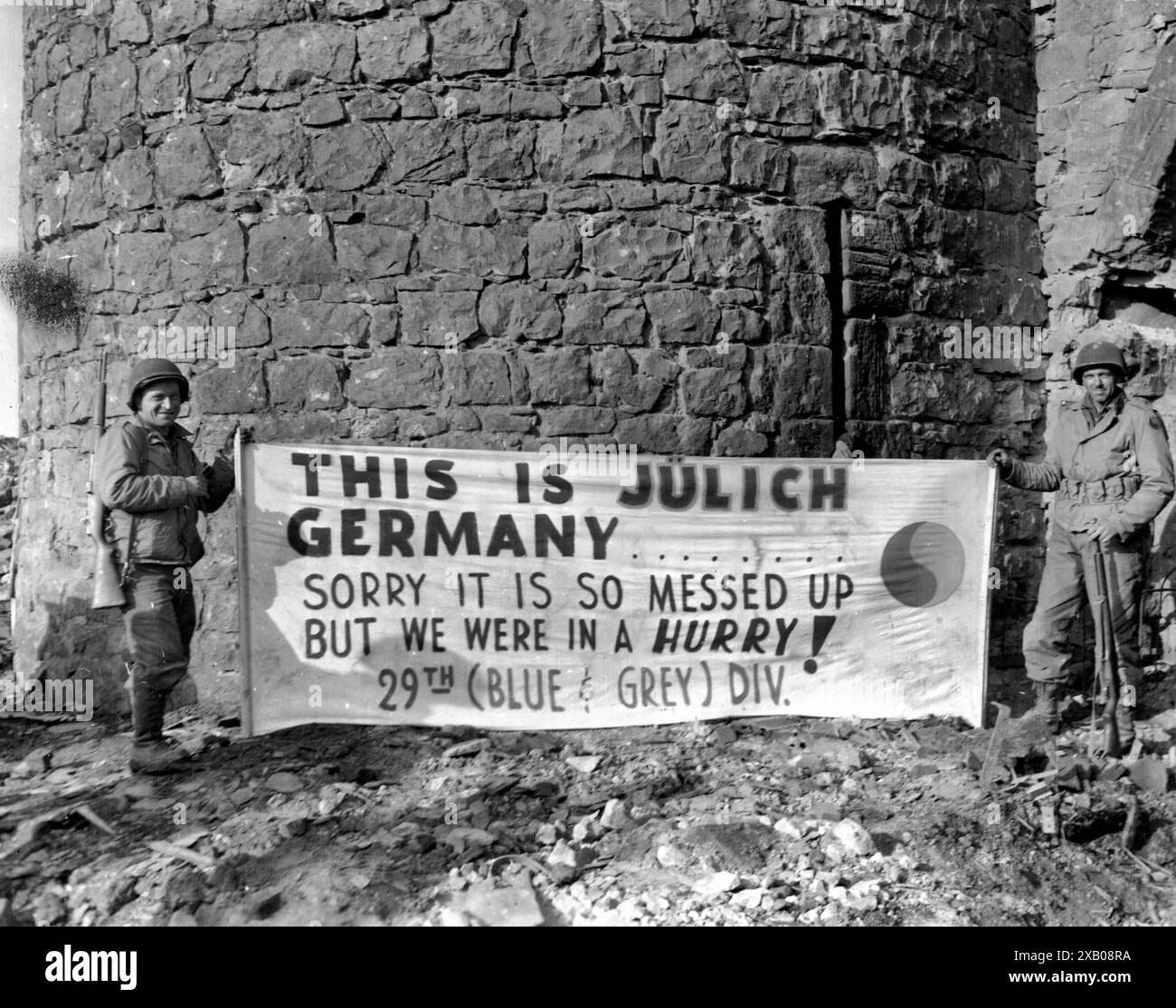 Mostra questo cartello di fronte alla cittadella di Julich, Germania - sulla PFC. Thomas Snyder, New York City, e Pvt. Paul Mattox, Washington, D.C., entrambi della compagnia C, 175th Infantry Regiment, 29th Infantry Division, Nona U.S. Army. 24 febbraio 1945. Compagnia C, 175th Infantry Regiment, 29th Infantry Division. Fotografo: T/4 Paul C. strong. Data 24 febbraio 1945 Foto Stock