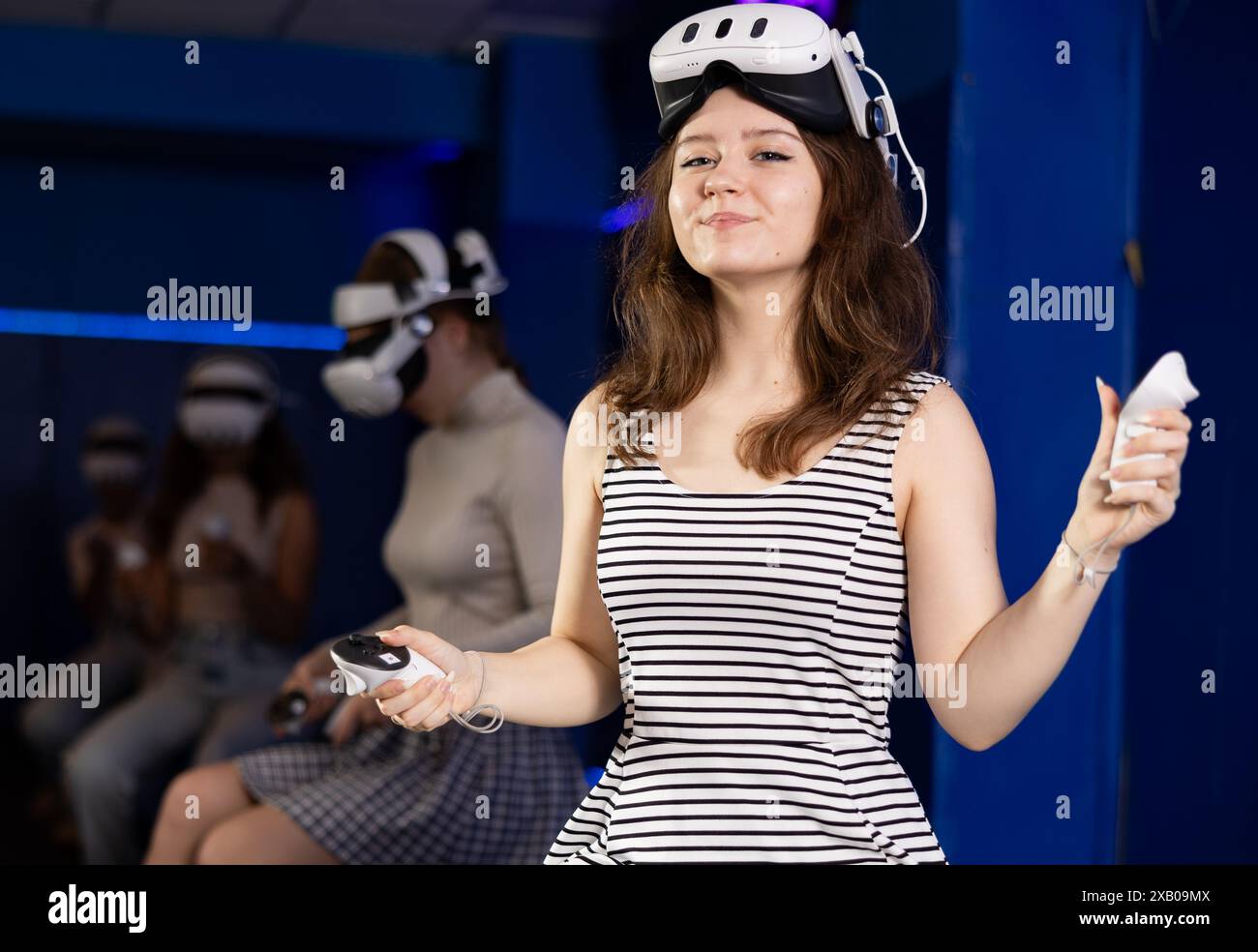 Allegra ragazza adolescente seduta nella sala giochi di realtà virtuale Foto Stock