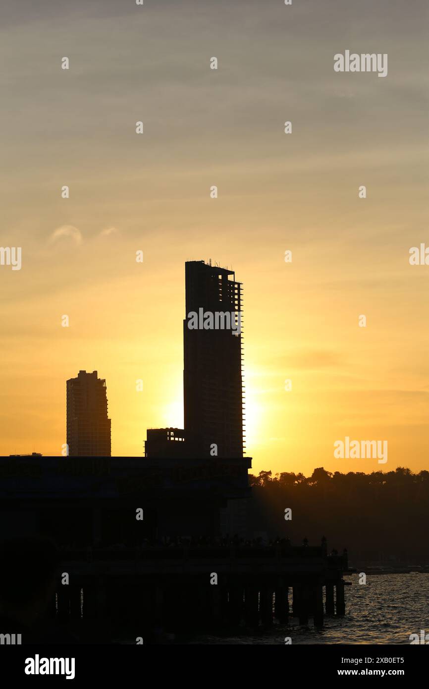 Immagine di alti edifici e montagne al sole della sera sta per tramontare, vista della città di Pattaya in stile silhouette. Foto Stock