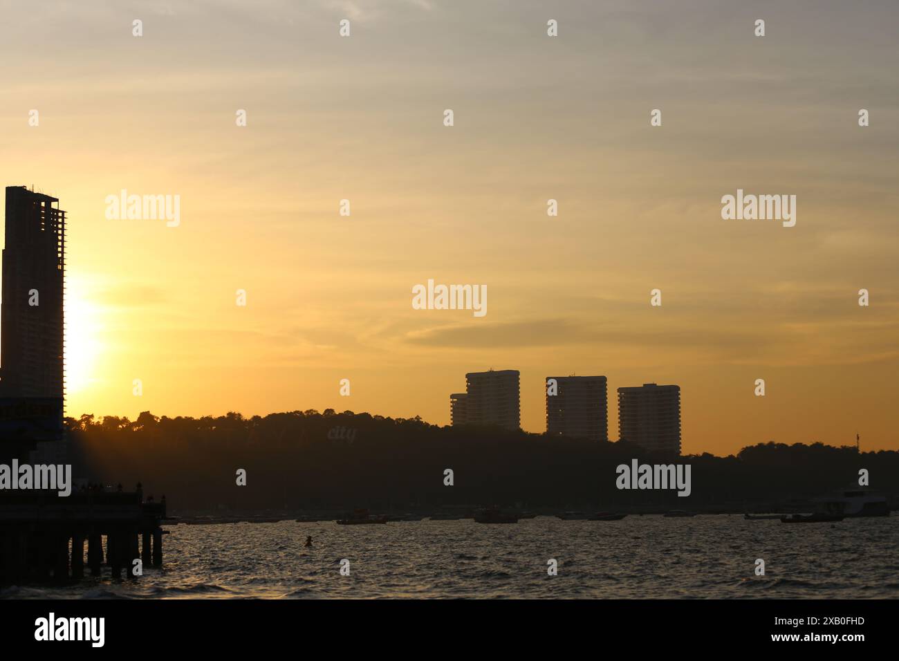 Immagine di alti edifici e montagne al sole della sera sta per tramontare, vista della città di Pattaya in stile silhouette. Foto Stock
