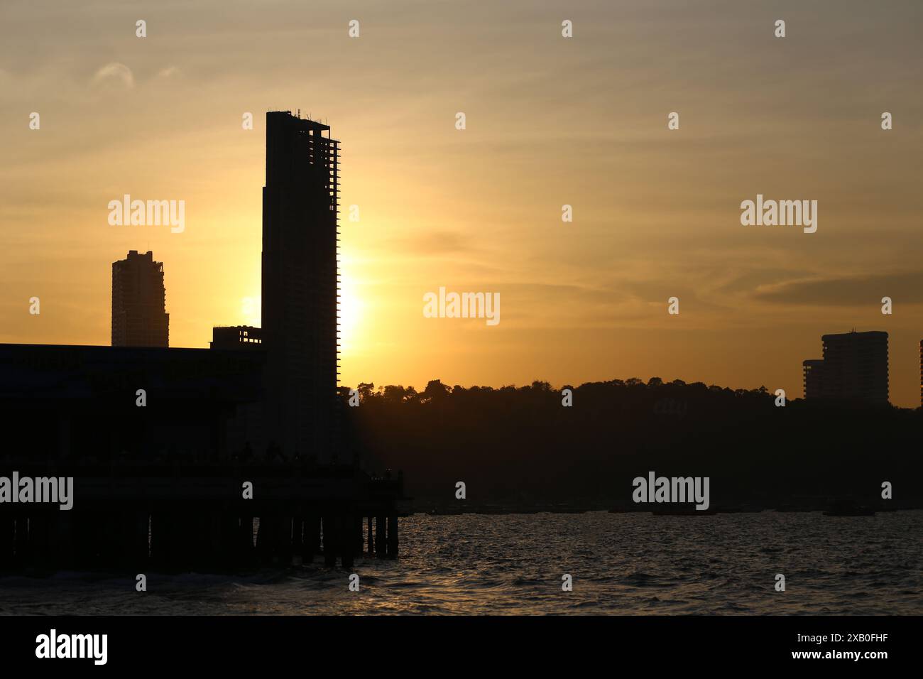 Immagine di alti edifici e montagne al sole della sera sta per tramontare, vista della città di Pattaya in stile silhouette. Foto Stock