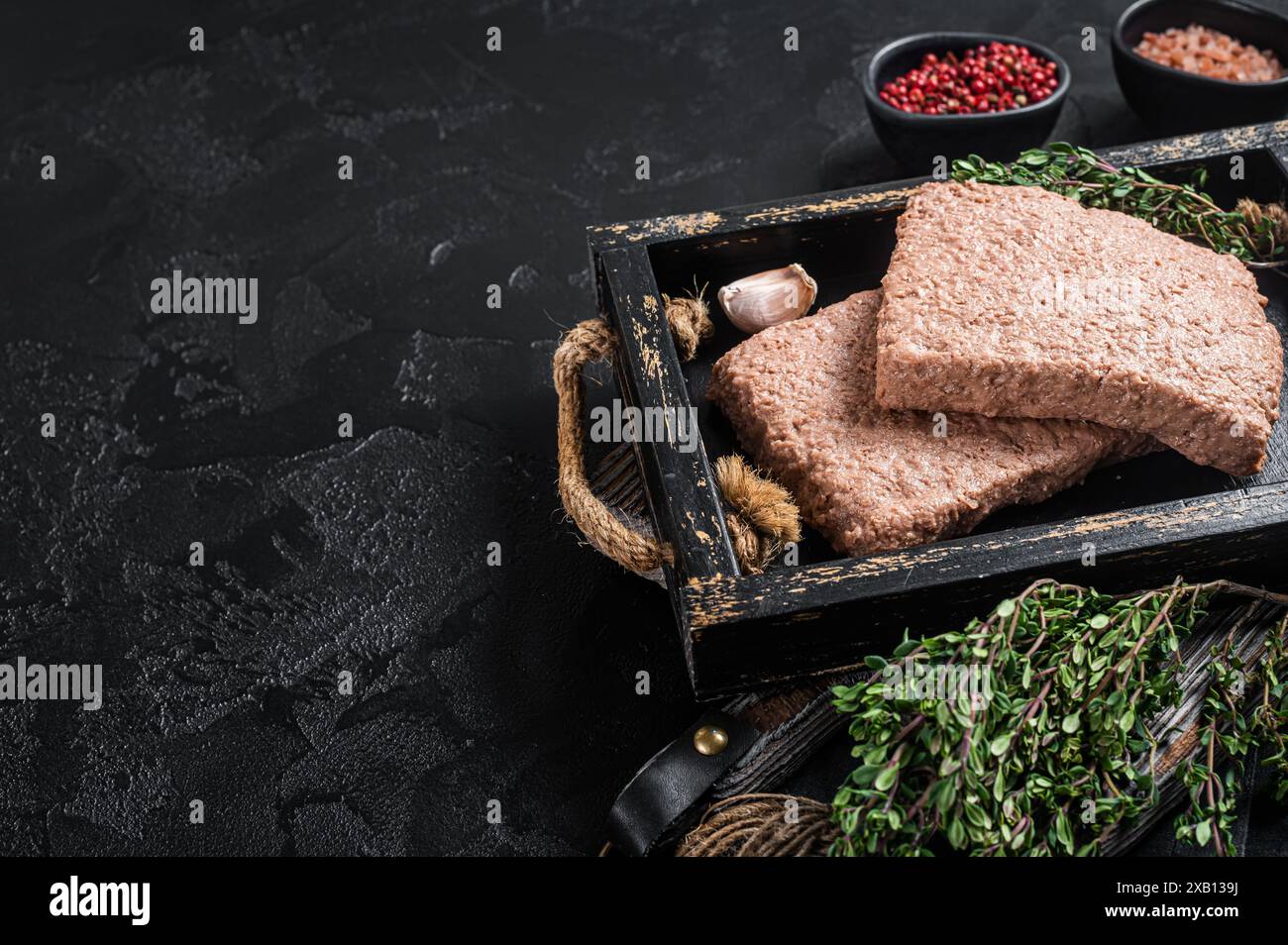 Carne vegana a base di piante crude con erbe aromatiche. Sfondo nero. Vista dall'alto. Spazio di copia. Foto Stock