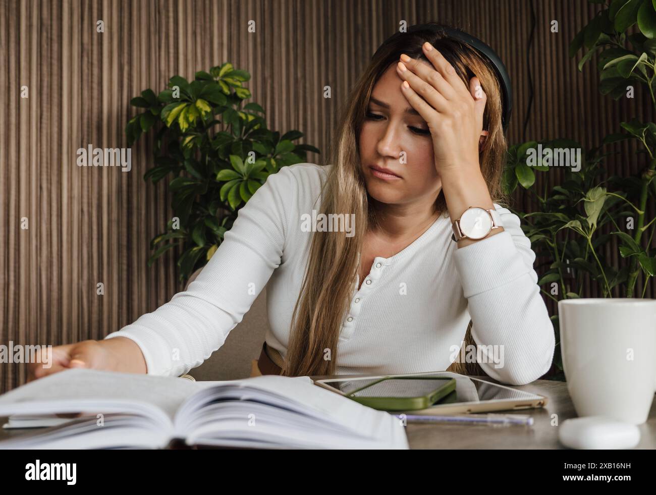 Donna stressata al lavoro, che tiene la testa sotto frustrazione mentre legge i documenti. Stress sul posto di lavoro e stress mentale. Pressione sul lavoro, salute mentale e sfide professionali. Foto Stock