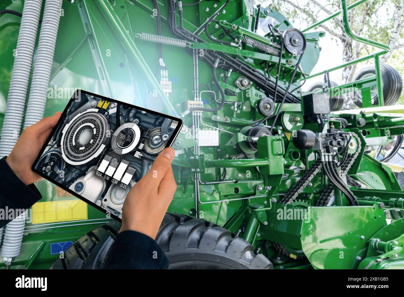 Addetto alla manutenzione con tablet digitale accanto alla mietitrebbia con cofano aperto Foto Stock