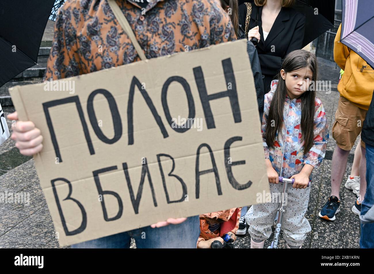 LEOPOLI, UCRAINA - 9 GIUGNO 2024 - Una ragazza guarda un dimostratore che tiene un cartello durante il Don't Be Silent! La prigionia uccide! raduno per ricordare il personale militare ucraino in prigionia russa, Leopoli, Ucraina occidentale. Foto Stock