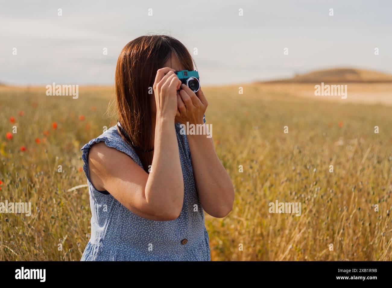 donna adulta delicata che usa la vecchia macchina fotografica per scattare foto. hobby. Giornata internazionale della fotografia Foto Stock