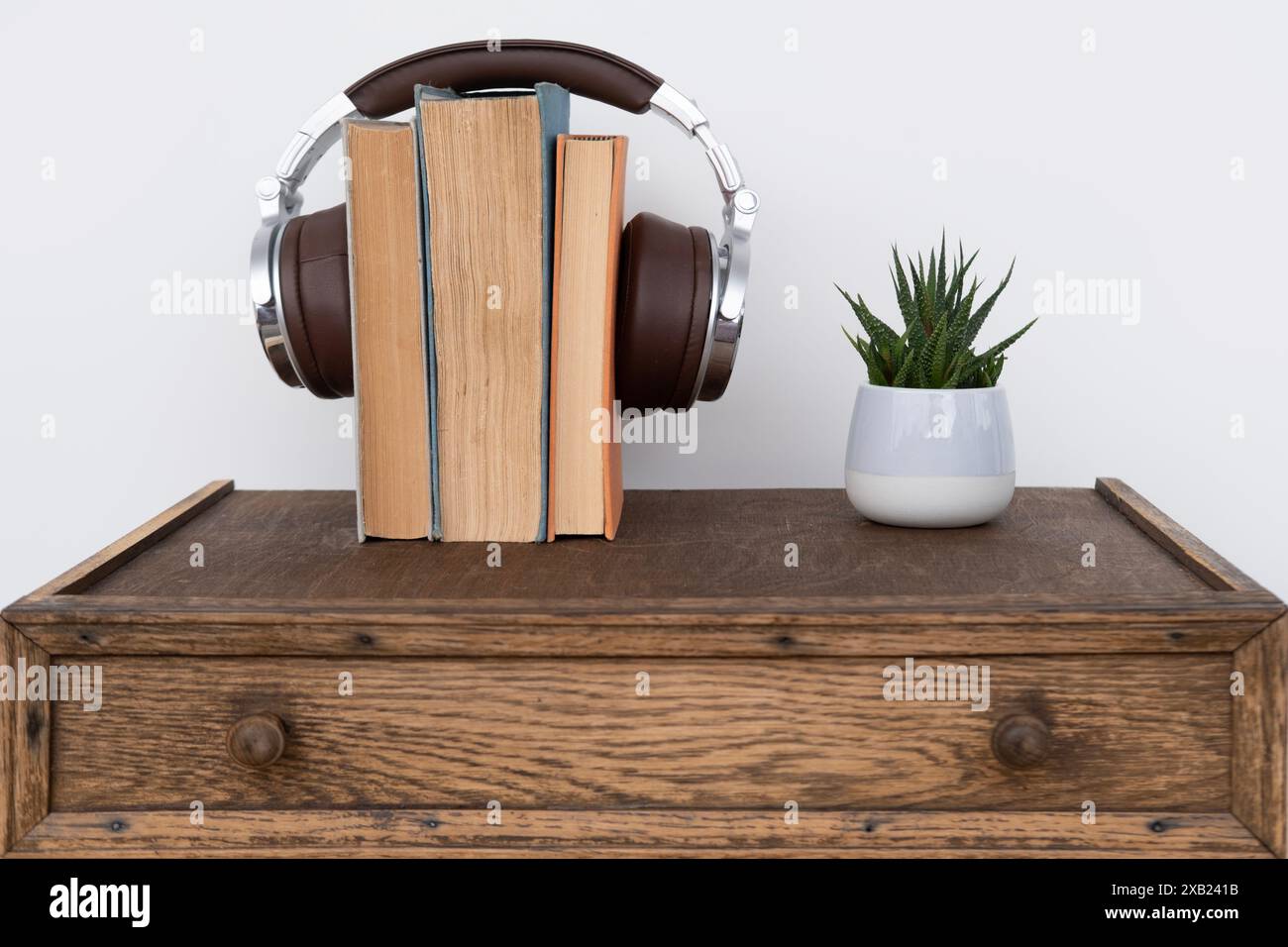 pila di libri con cuffie, apprendimento di lingue straniere con audiobook, apprendimento multimediale, sviluppo di capacità di lettura e ascolto, tecnologia Foto Stock