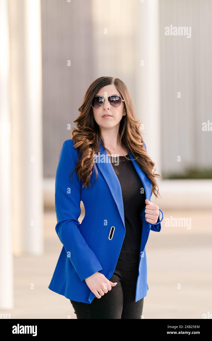 Donne d'affari che indossano occhiali da sole e blazer blu che guardano in alto Foto Stock
