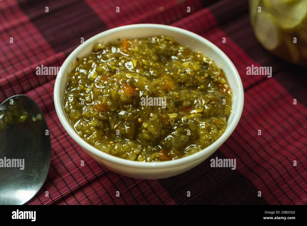 assapora il sottaceto dolce in un recipiente bianco, trita grossolana di cetriolo, pepe e cipolla con salamoia all'aceto dolce Foto Stock