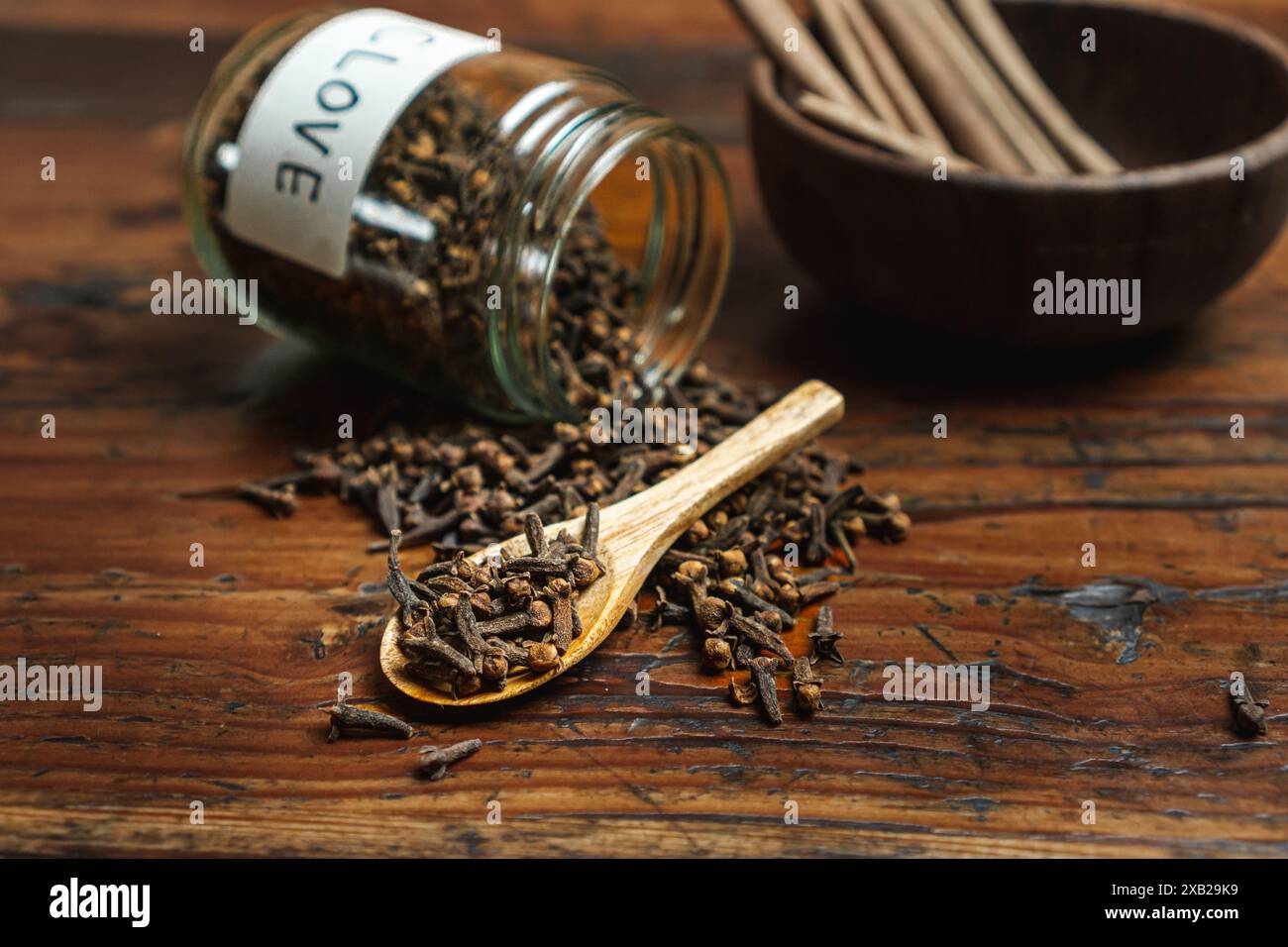 Cospargere il barattolo di vetro delle spezie sopra il bambù intrecciato rosso e la cannella su un recipiente, in base al concetto di utilizzo delle spezie in cucina Foto Stock