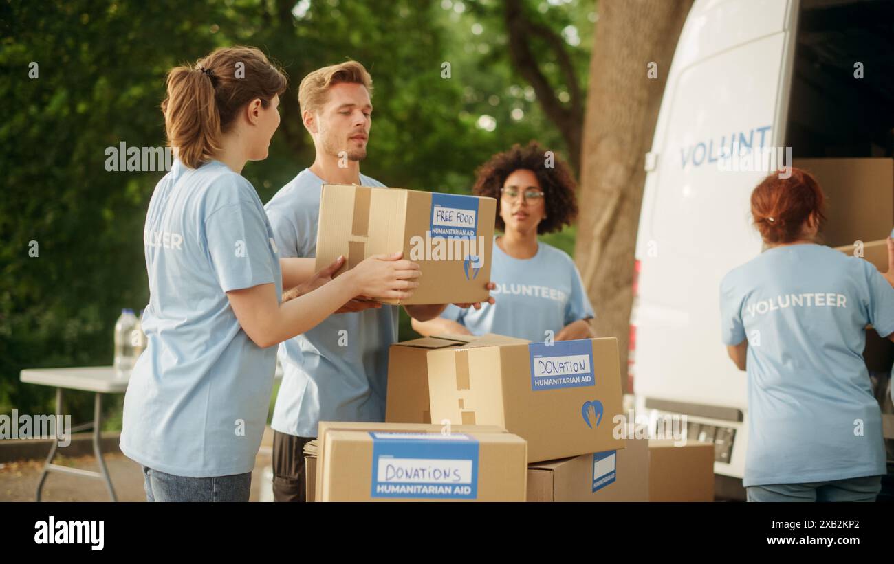 Felice gruppo di volontari che lavorano per consegnare aiuti umanitari e donazioni, caricare scatole su un furgone da carico. I lavoratori di beneficenza di successo fanno cinque l'uno con l'altro. Foto Stock