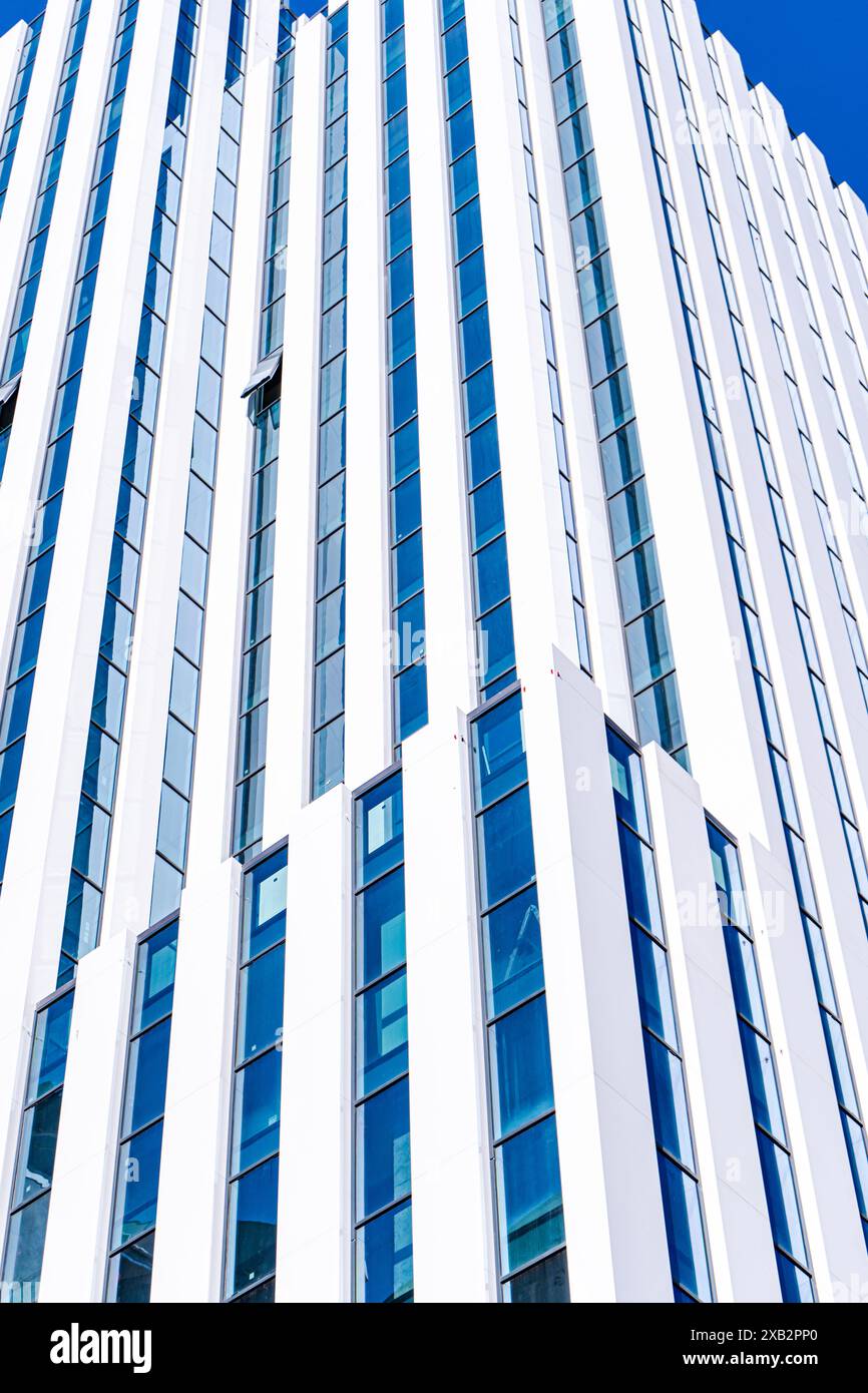 Un alto e contemporaneo edificio a Tbilisi, la capitale della Georgia, che presenta linee verticali e finestre blu riflettenti sotto un cielo limpido Foto Stock