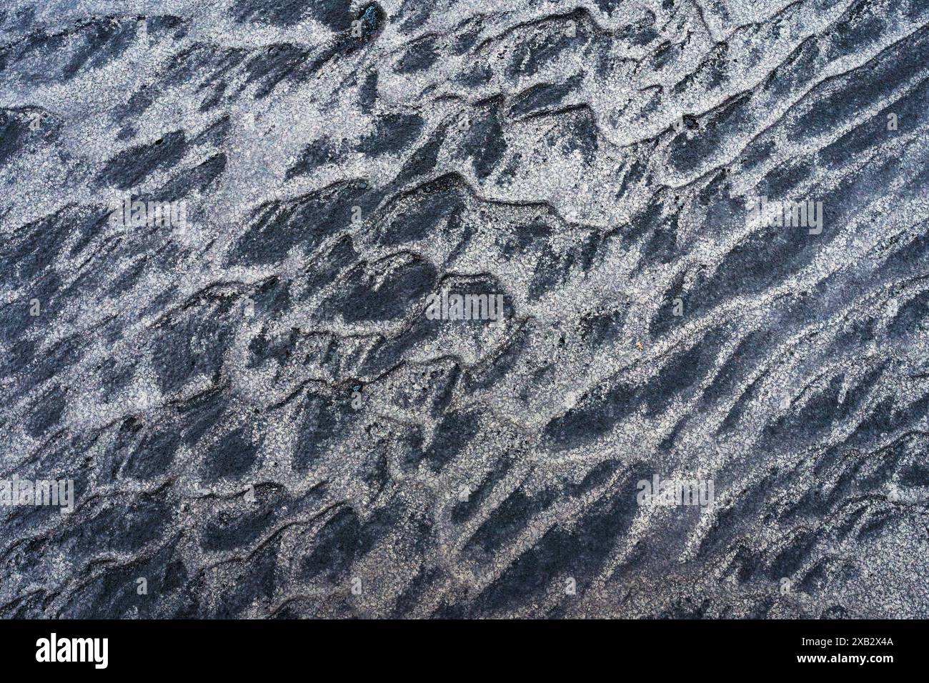 Uno sguardo dettagliato alle texture di sabbia scolpite naturalmente, rivelando un motivo unico di creste e valli su un vasto terreno montuoso Foto Stock