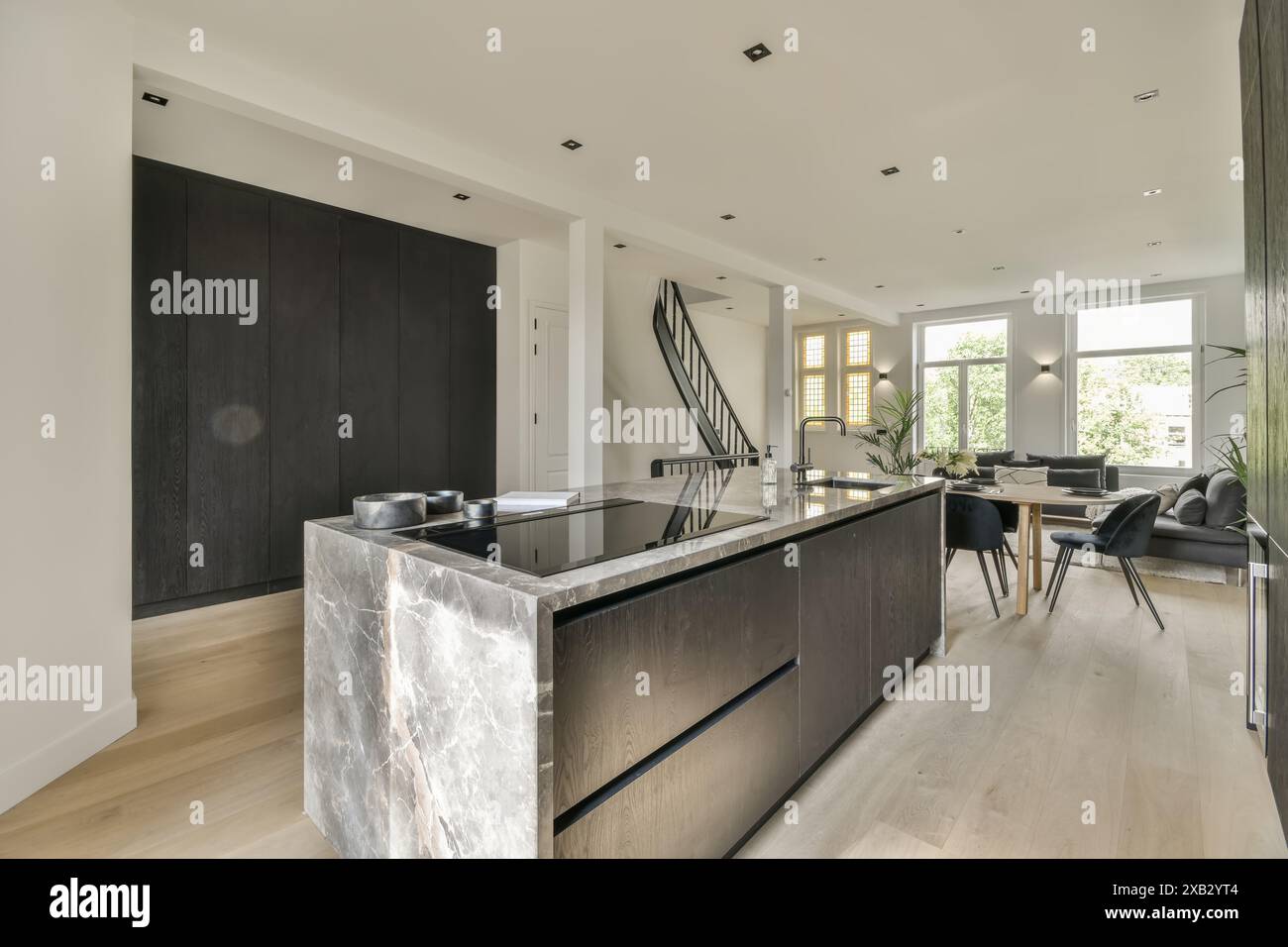 Elegante cucina contemporanea con isola in marmo e elettrodomestici integrati in interni luminosi con arredi eleganti e pavimenti in legno duro. Foto Stock