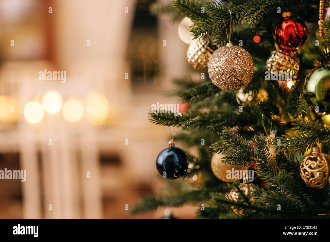 Primo piano di un albero di Natale decorato con giocattoli in vetro vintage. Interni eleganti e ricchi con caminetto e candele accese. Decorazioni per l'anno nuovo. Copia Foto Stock