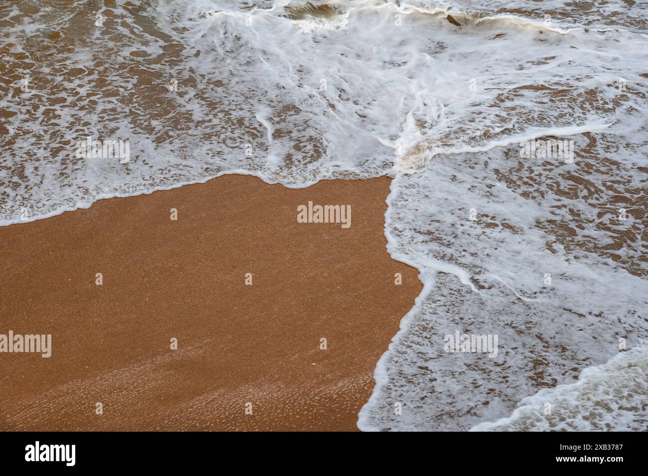 Acque poco profonde e sabbia sullo sfondo delle vacanze, onde spumeggianti che coprono una spiaggia da due lati. Foto Stock