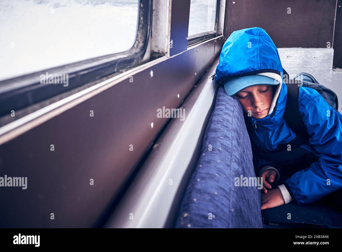 Ragazzo stanco che indossa una giacca blu che dorme nel veicolo Foto Stock