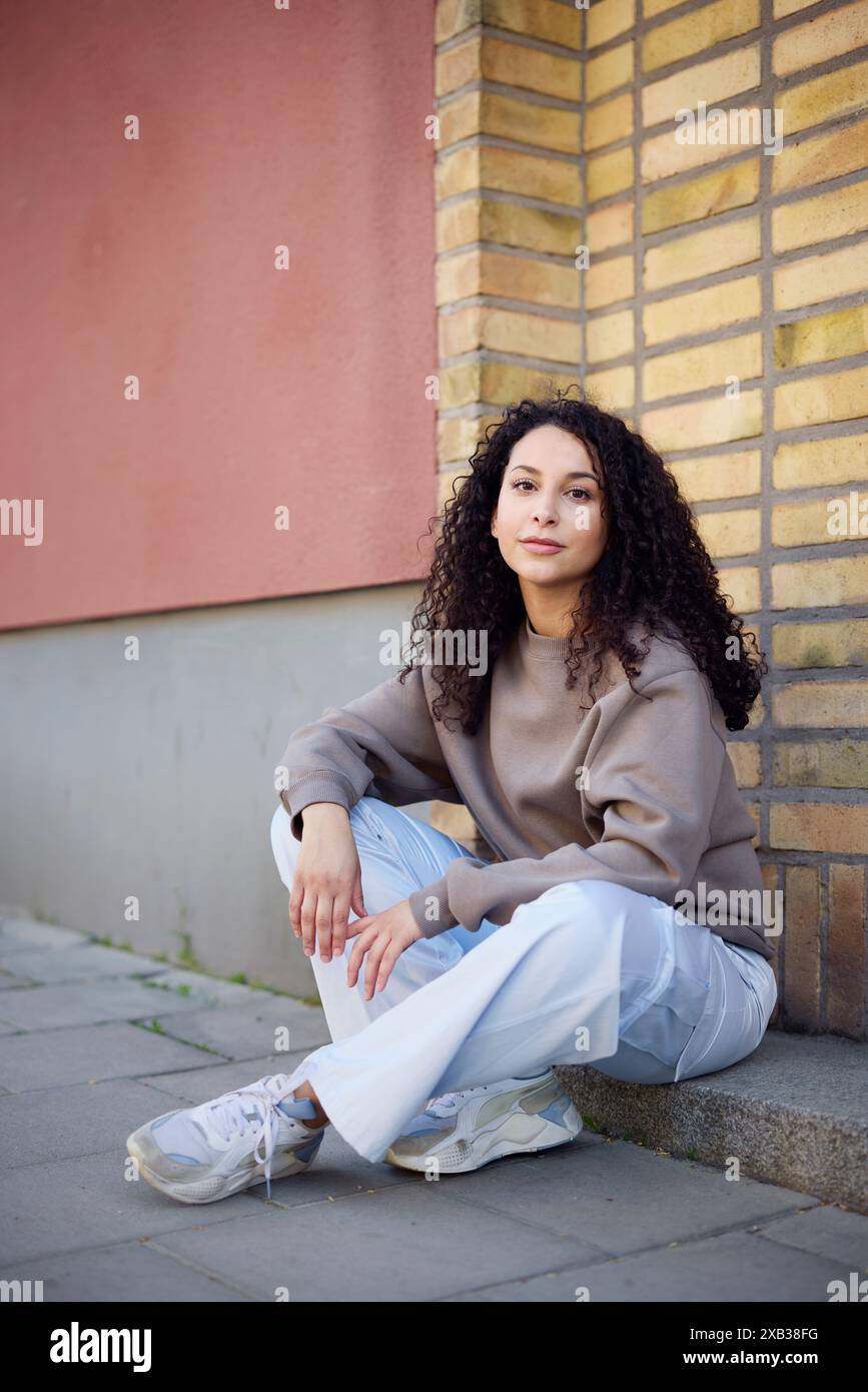 Bella donna sorridente seduta sul sentiero Foto Stock