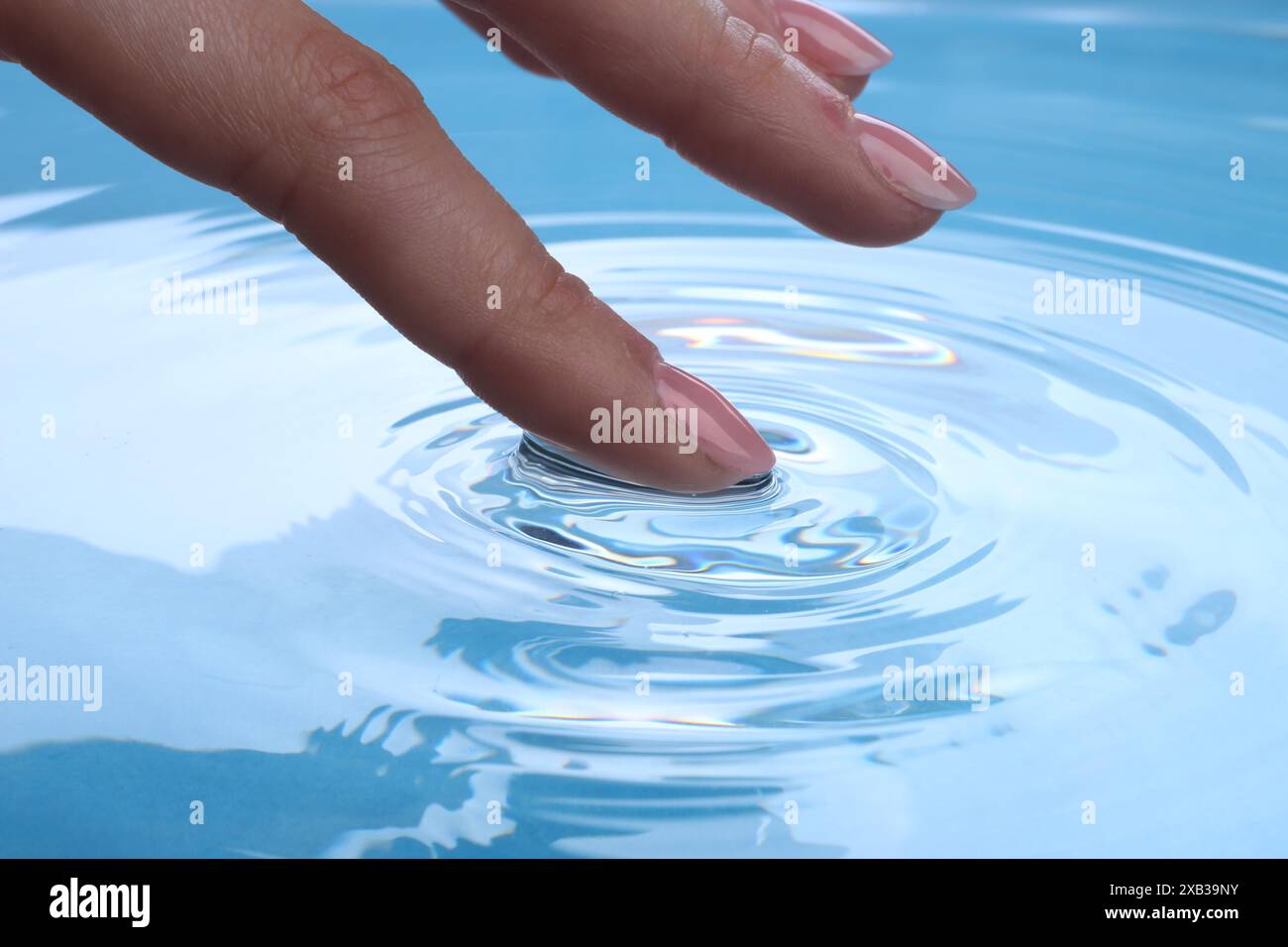 Donna che tocca l'acqua limpida, primo piano. Creare increspature Foto Stock