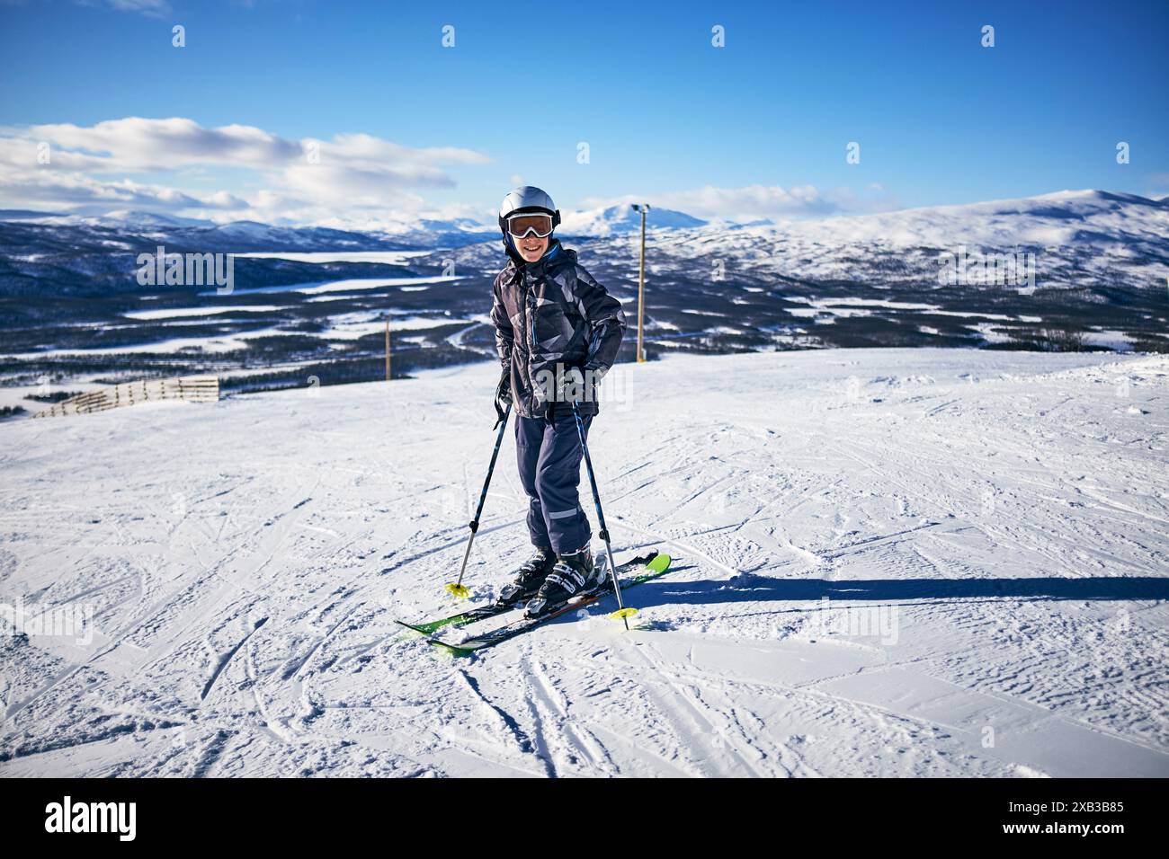 Ragazzo felice con abiti caldi che sciano su un terreno innevato Foto Stock