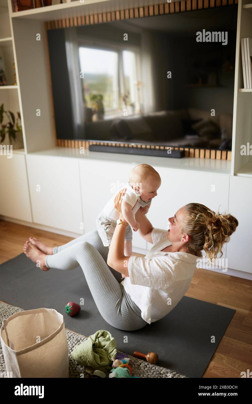 Vista ad alto angolo di madre e figlio sul tappetino da ginnastica nel soggiorno di casa Foto Stock