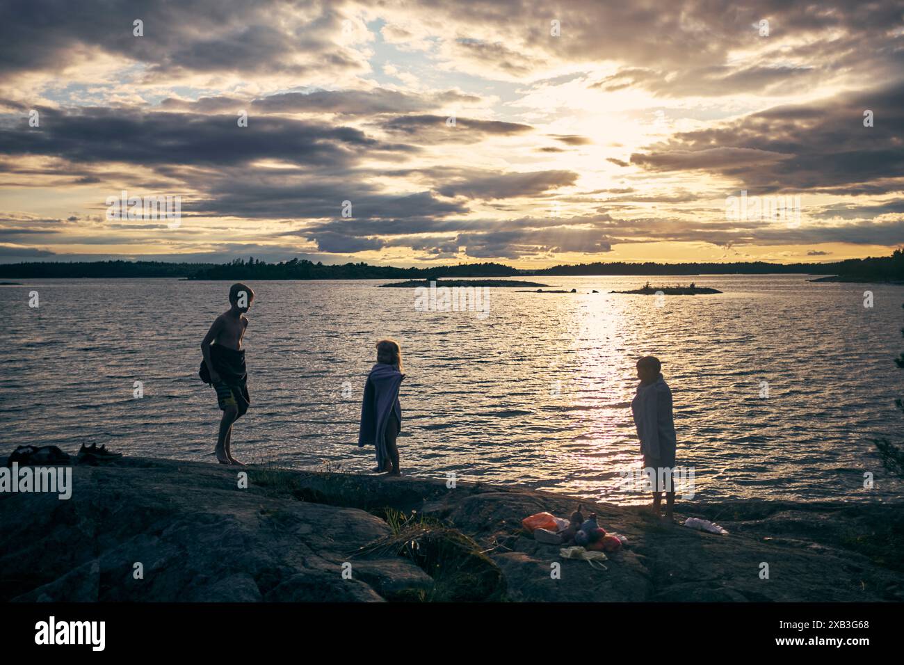 Fratelli sulla formazione rocciosa via mare contro il cielo nuvoloso al tramonto Foto Stock