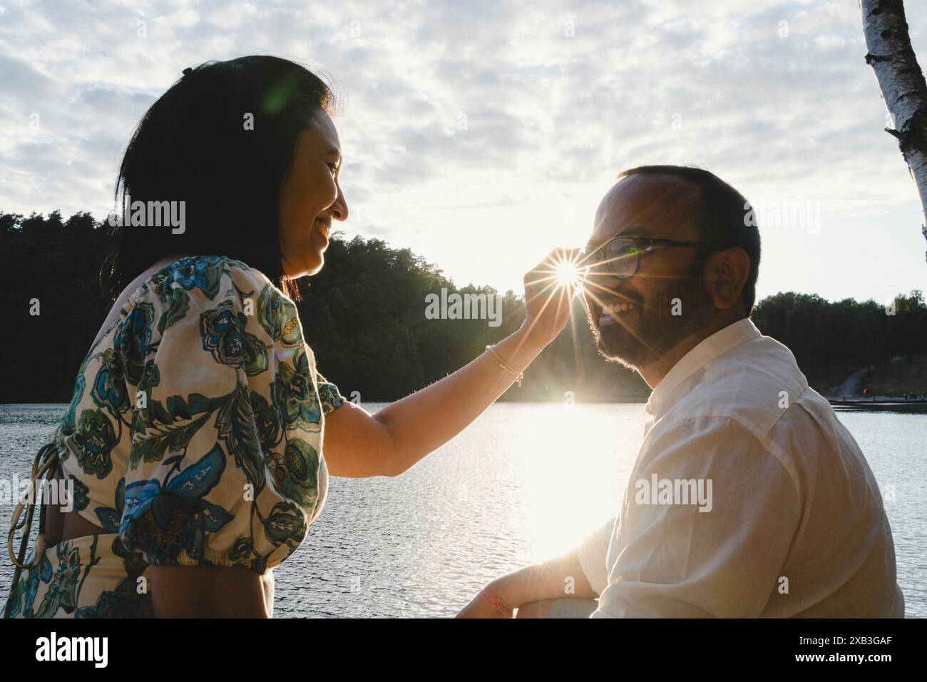 Donna felice che tocca gli occhiali da vista dell'uomo nelle giornate di sole Foto Stock