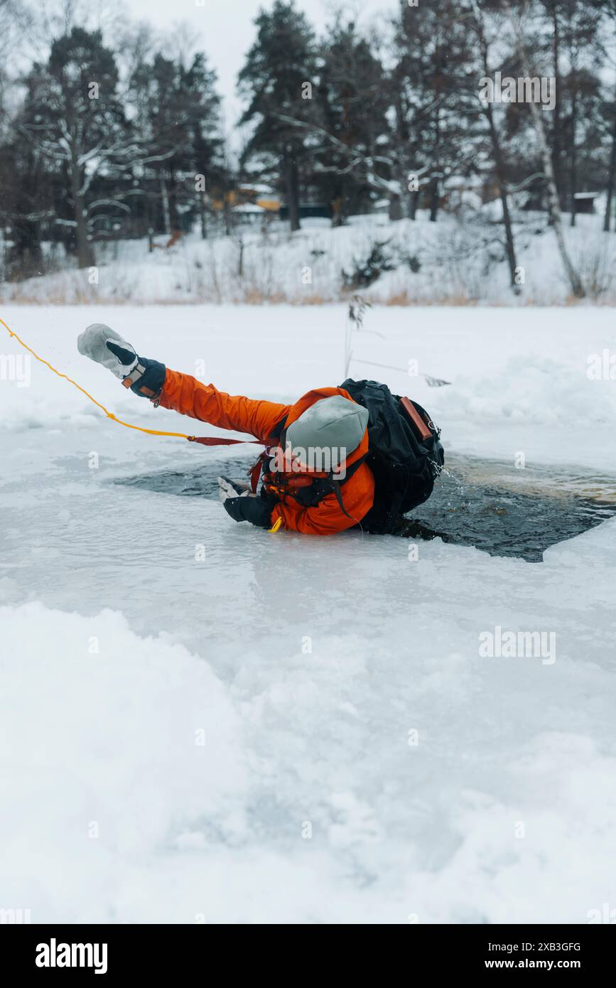 Donna che prende e esce dall'acqua ghiacciata del lago in inverno Foto Stock