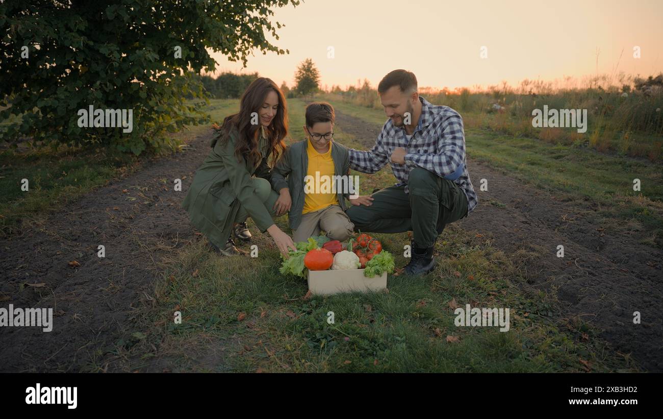 Sano felice Caucasico famiglia contadino coppia donna donna madre padre maschio uomo abbraccio bambino bambino bambino bambino bambino seduto mettere verdure mature alimentari eco-food Foto Stock