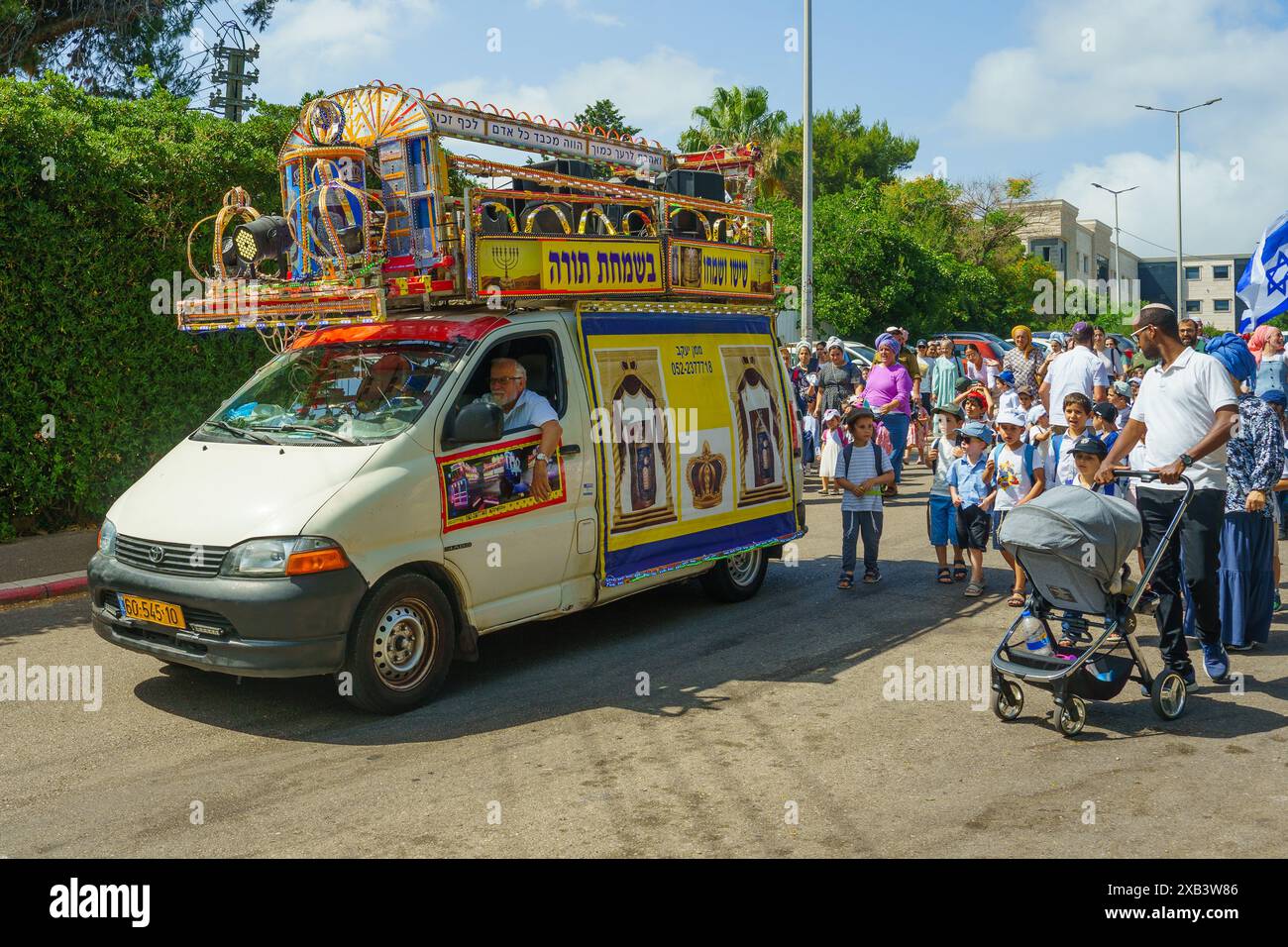 Haifa, Israele - 09 giugno 2024: Ebrei ortodossi, per lo più bambini, celebrano con un libro sacro della Torah nelle strade di Haifa, Israele Foto Stock
