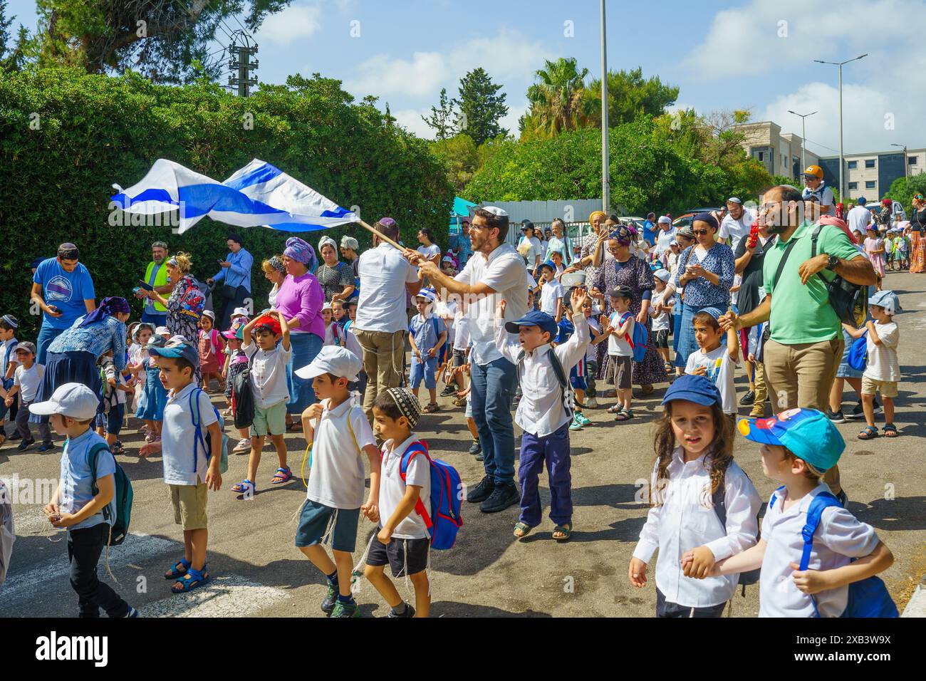 Haifa, Israele - 09 giugno 2024: Ebrei ortodossi, per lo più bambini, celebrano con un libro sacro della Torah nelle strade di Haifa, Israele Foto Stock