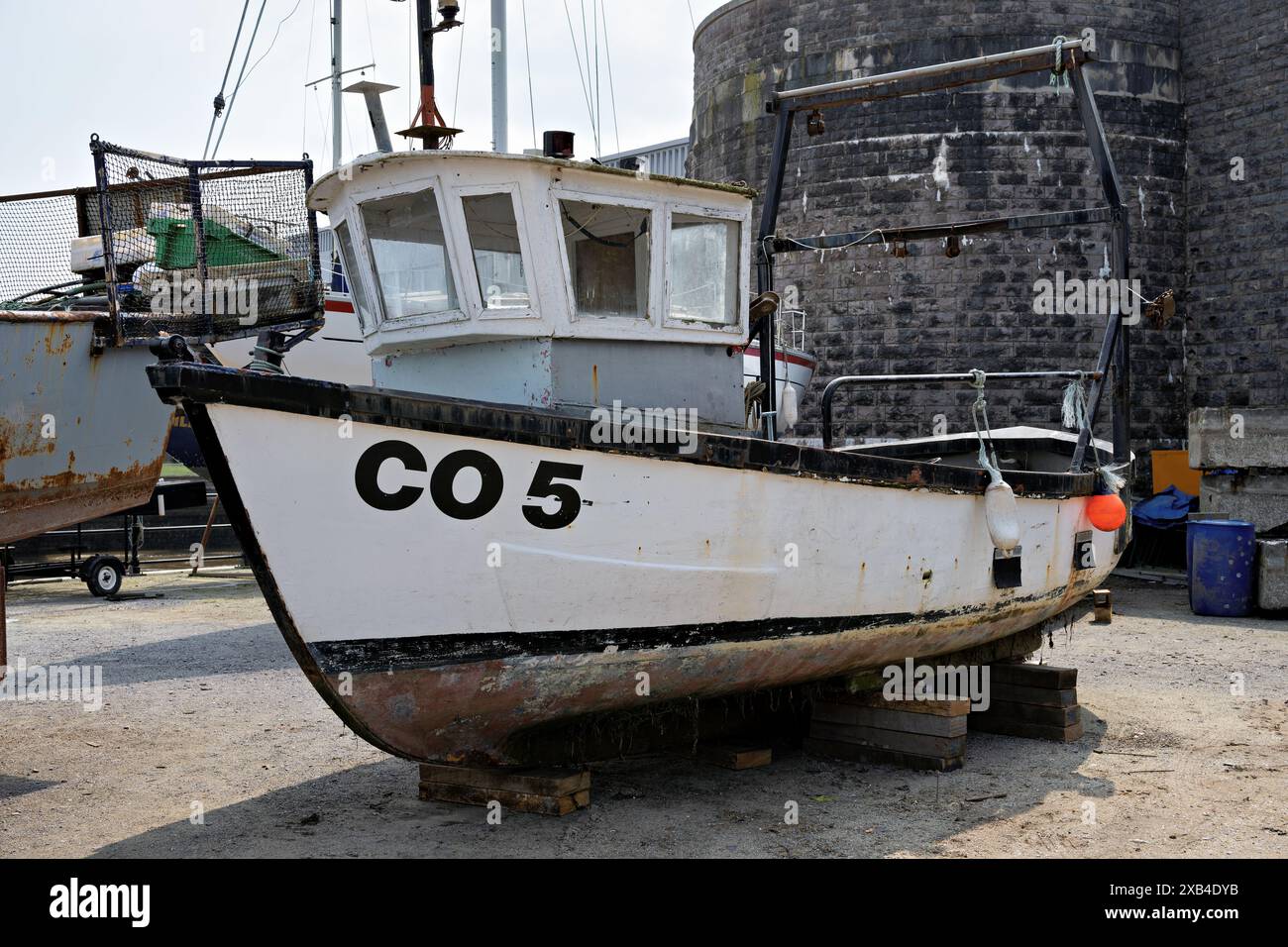 Conwy Wales Regno Unito 06-01-2024. La vecchia barca da pesca "CO 5" è ancorata su blocchi di legno con pareti in pietra e attrezzature marine nelle vicinanze Foto Stock