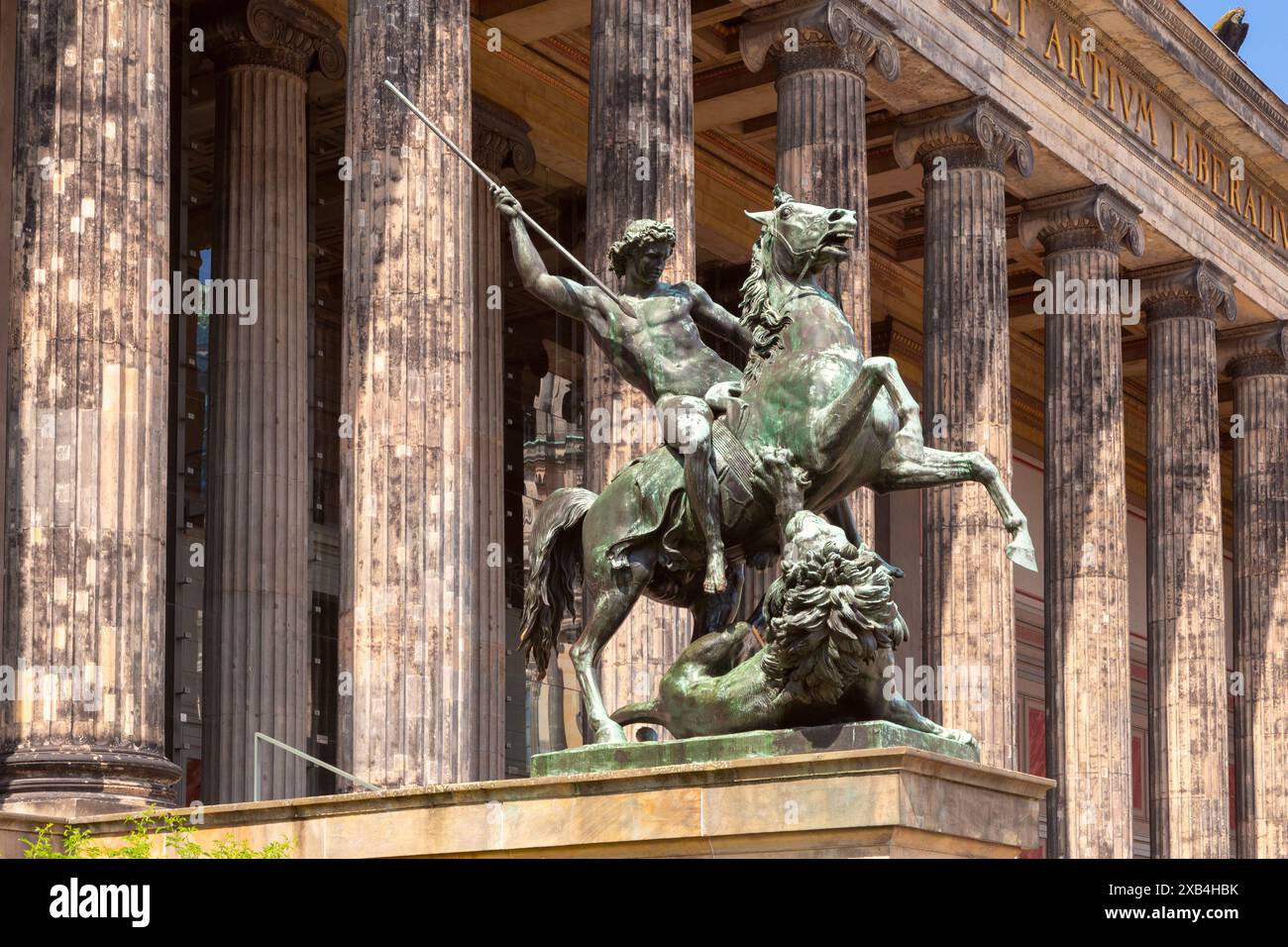 Berlino, Germania - 23 maggio 2024: Scultura in bronzo di un cavaliere di fronte al museo storico di manufatti greci sull'Isola dei Musei in una giornata di sole. Foto Stock