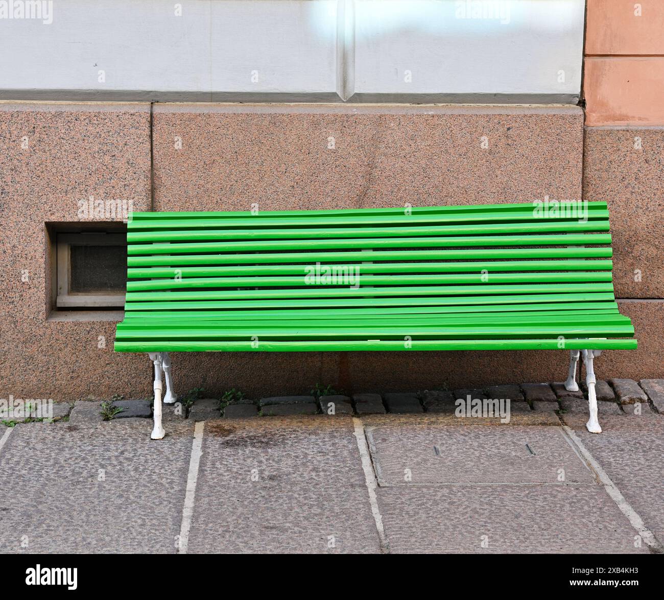 Panca verde brillante su pavimentazione in granito vicino alla fondazione in granito di una casa a Helsinki, Finlandia Foto Stock